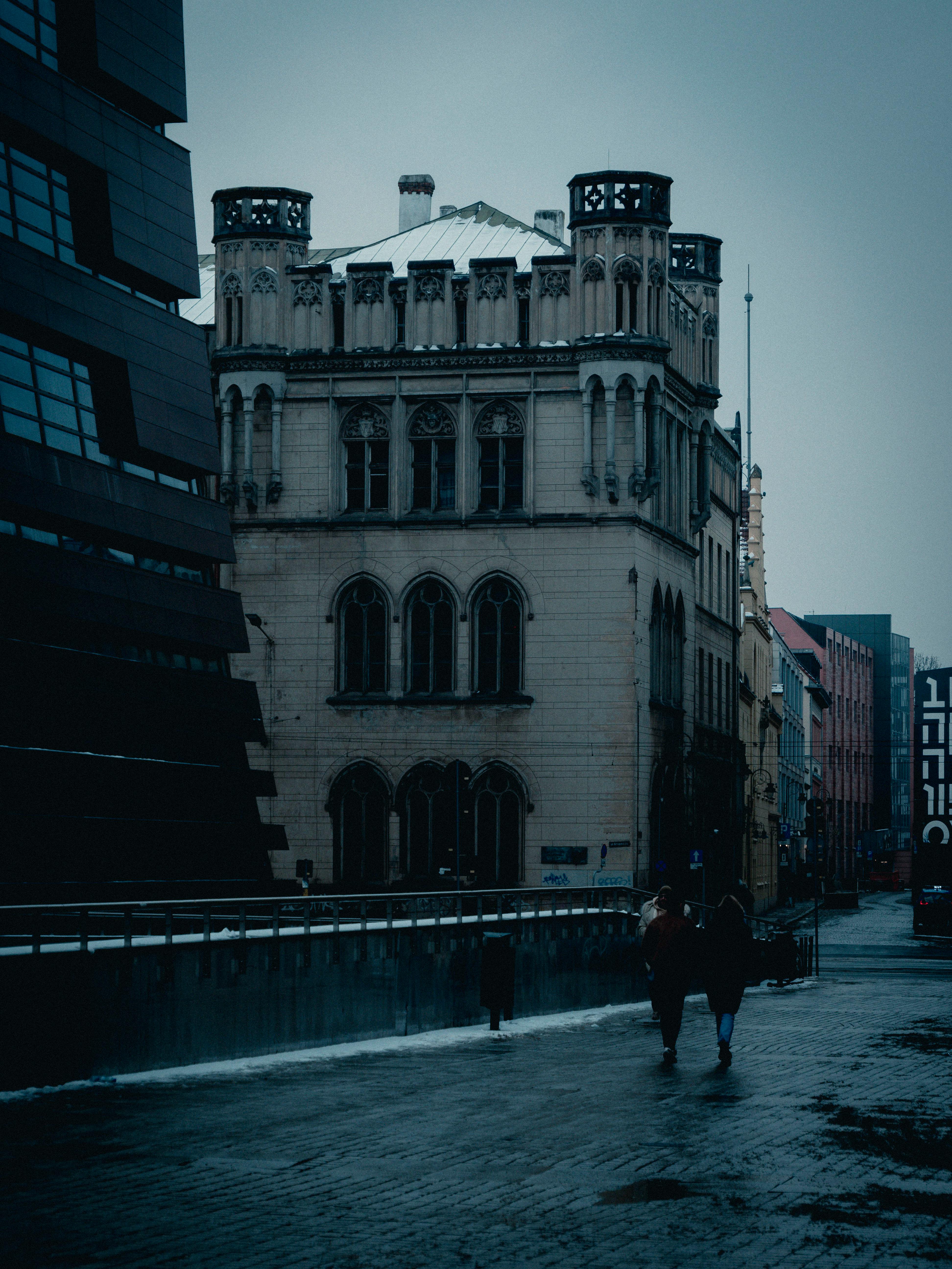 Gratis Edificio de estilo gótico a lo largo de una calle de la ciudad con una atmósfera crepuscular melancólica. Foto de stock