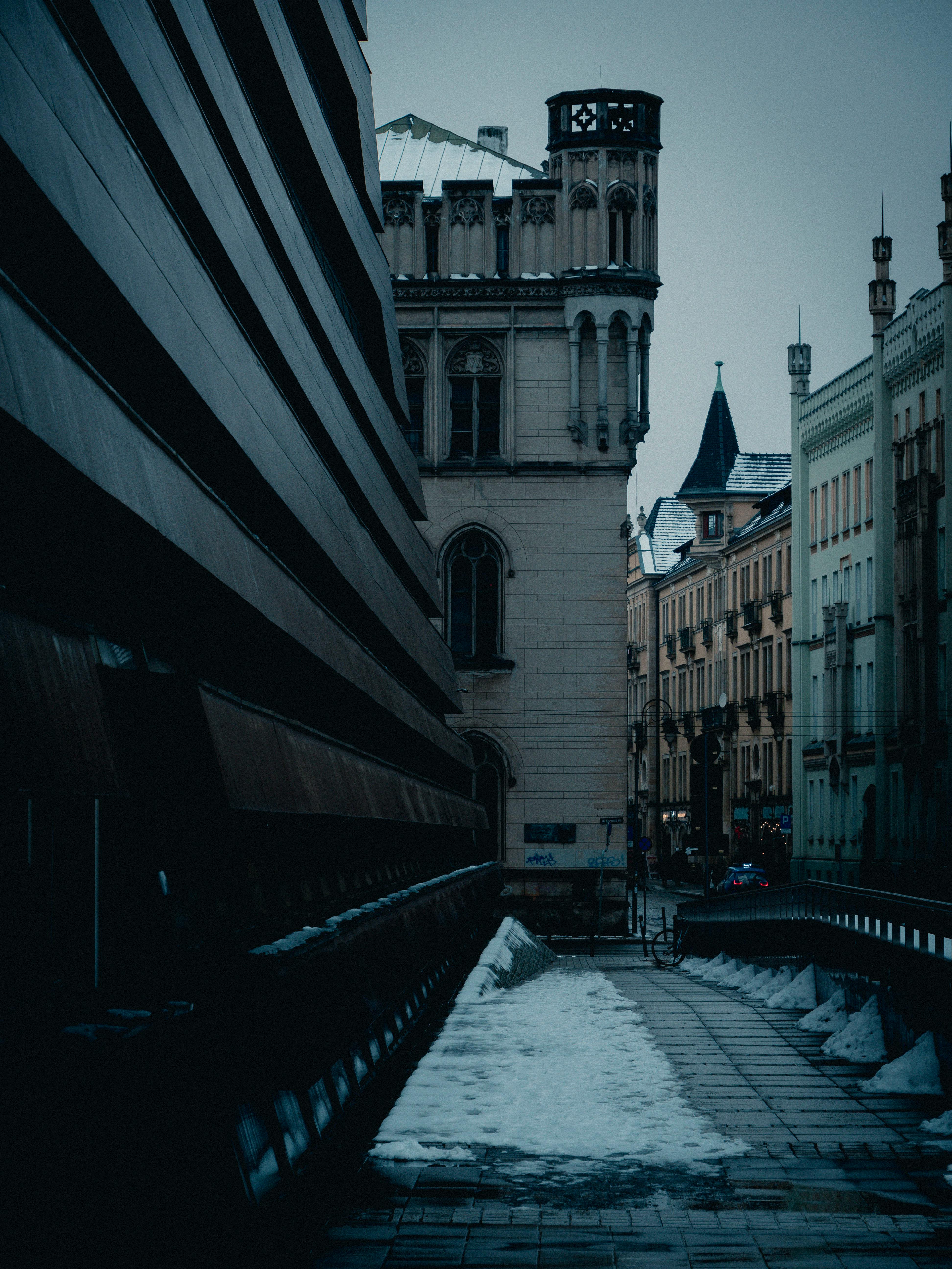 bezplatná Dramatická ulička s gotickou architekturou a sněhem pod ponurou zimní oblohou. Základová fotografie