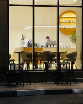 Warm ambiance of a modern cafe in Al Khobar at night with a barista preparing drinks.