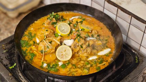 Free A flavorful chicken curry garnished with lemons and spices, cooked to perfection in a sizzling pan. Stock Photo