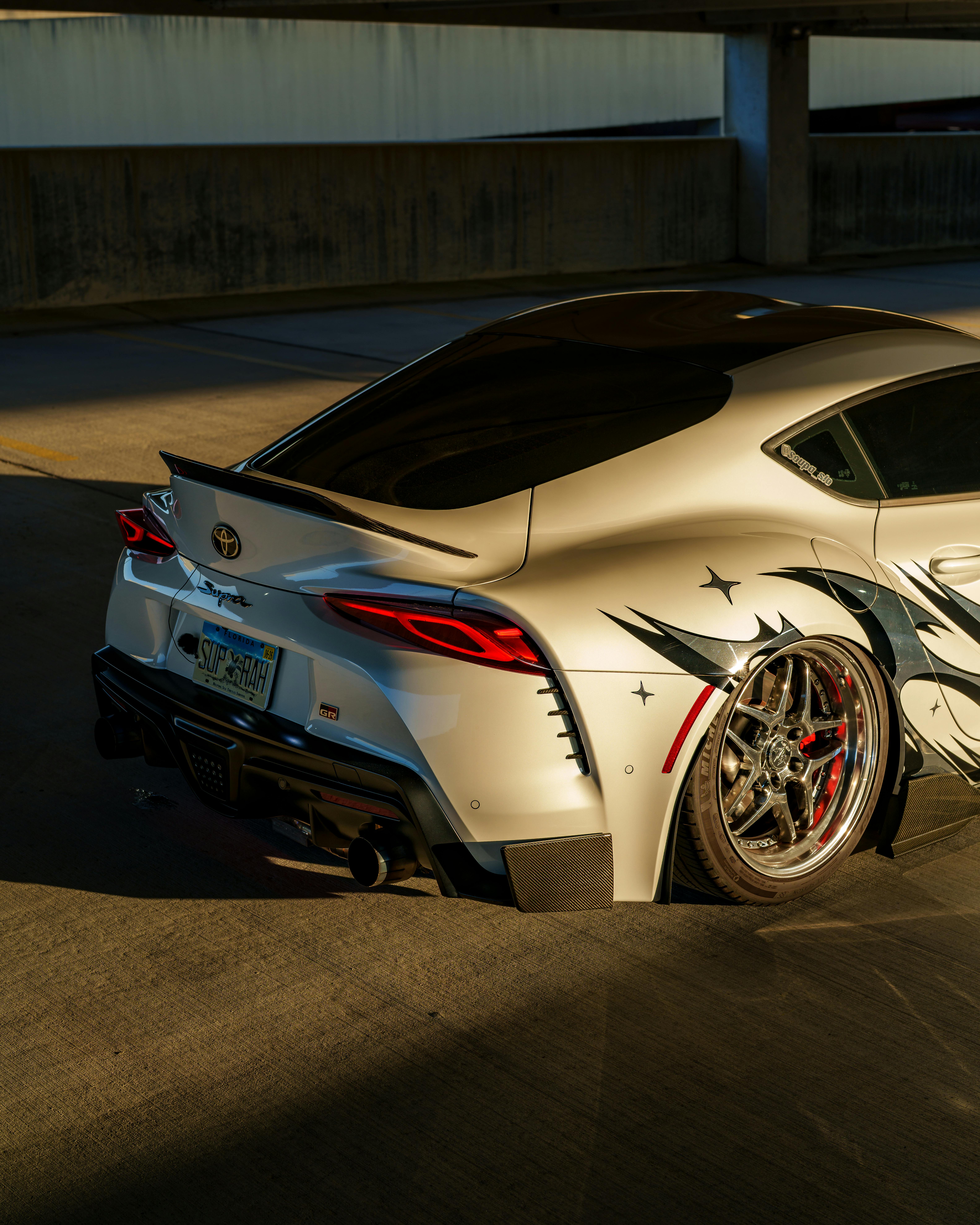 Ilmainen Muokattu urheiluauto, jossa on mittatilaustyönä tehty muotoilu, pysäköitynä kaupungin pysäköintihalliin auringonlaskun aikaan. Kuvapankkikuva