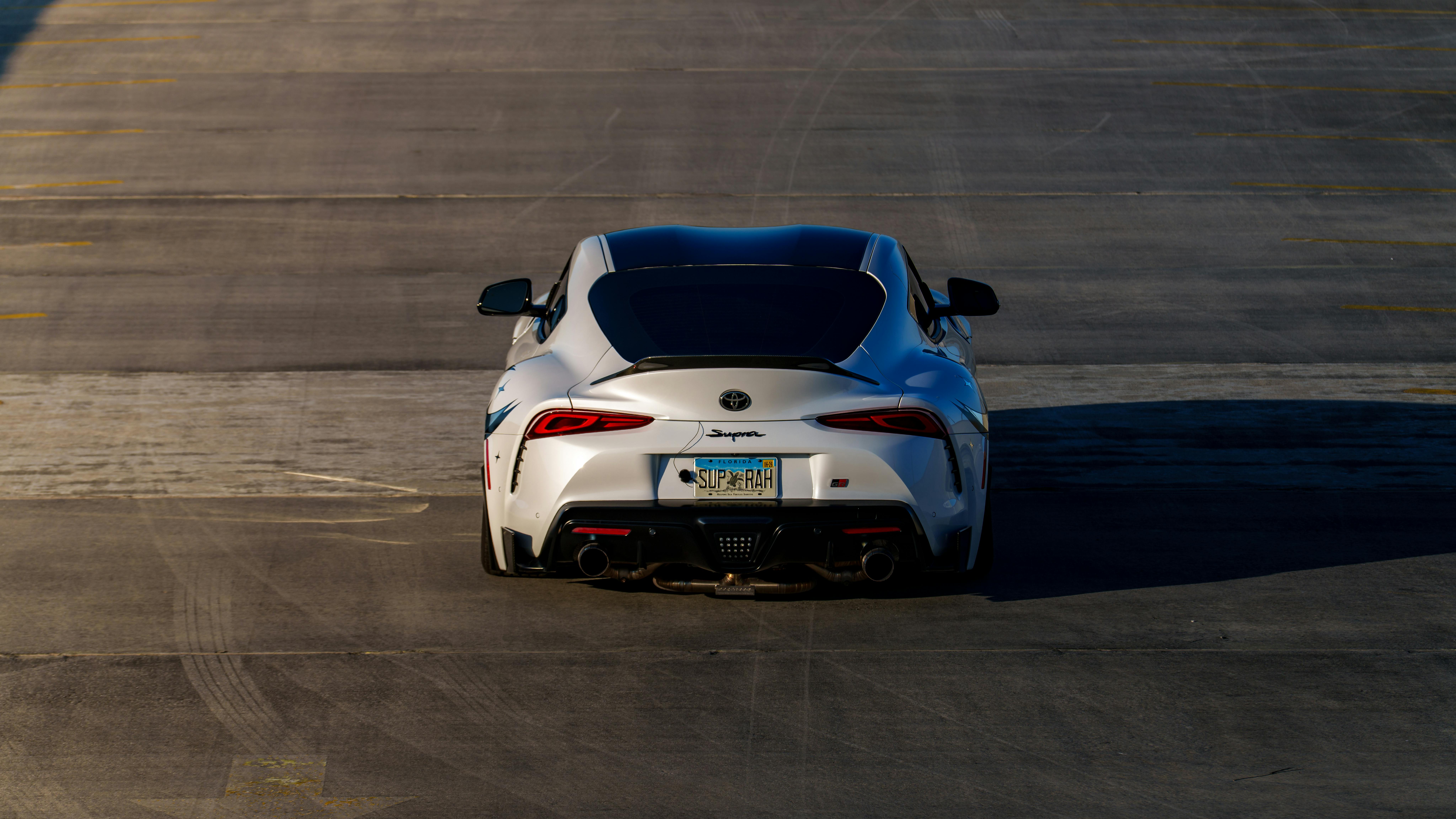 A white sports car parked on an empty asphalt lot, highlighting its sleek design.