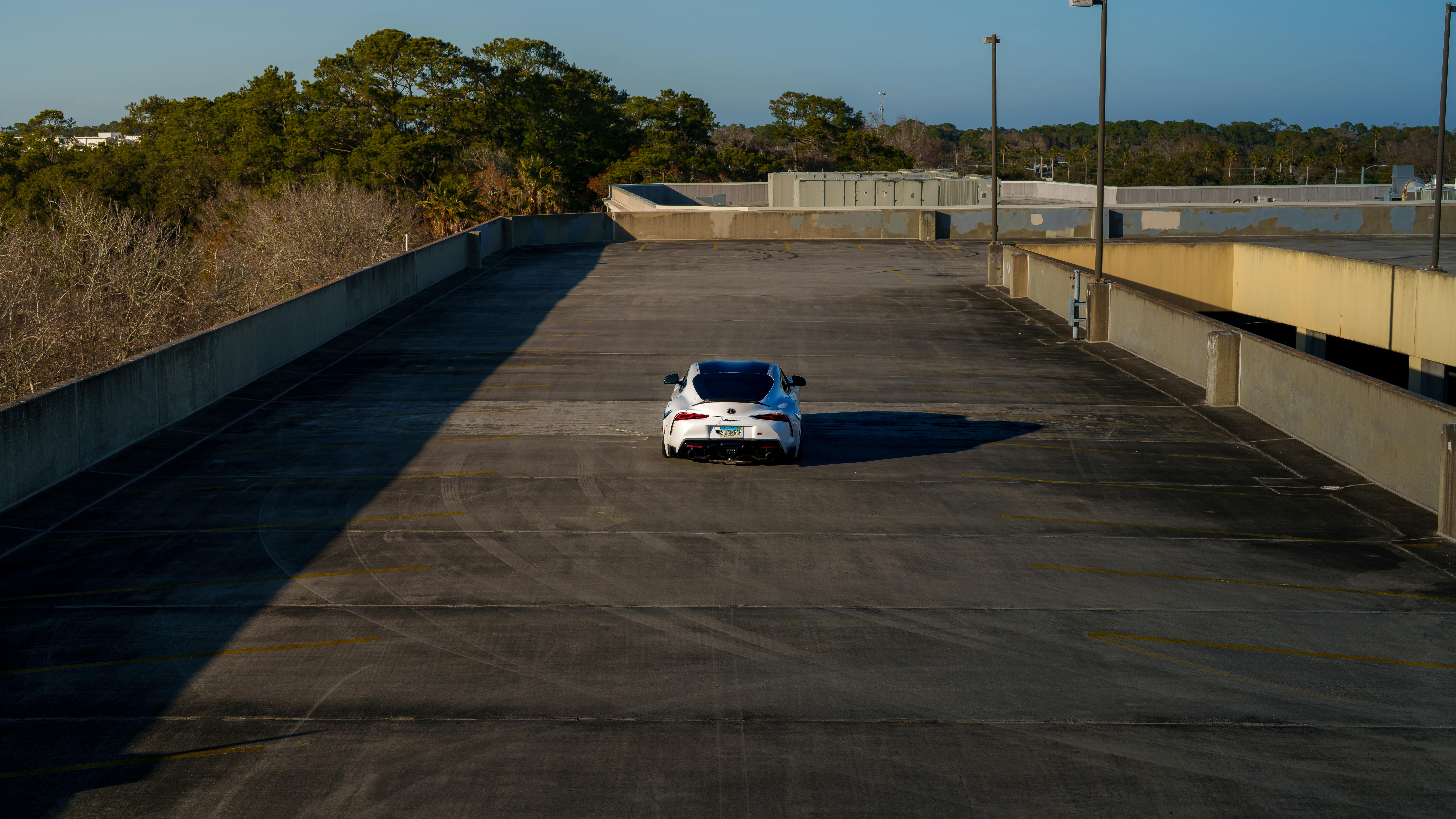 Gratis Un'auto bianca parcheggiata su un parcheggio vuoto sul tetto in una giornata limpida. Foto a disposizione