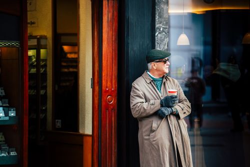 Free Elderly man in a trench coat holding coffee on a Dublin street. Stock Photo