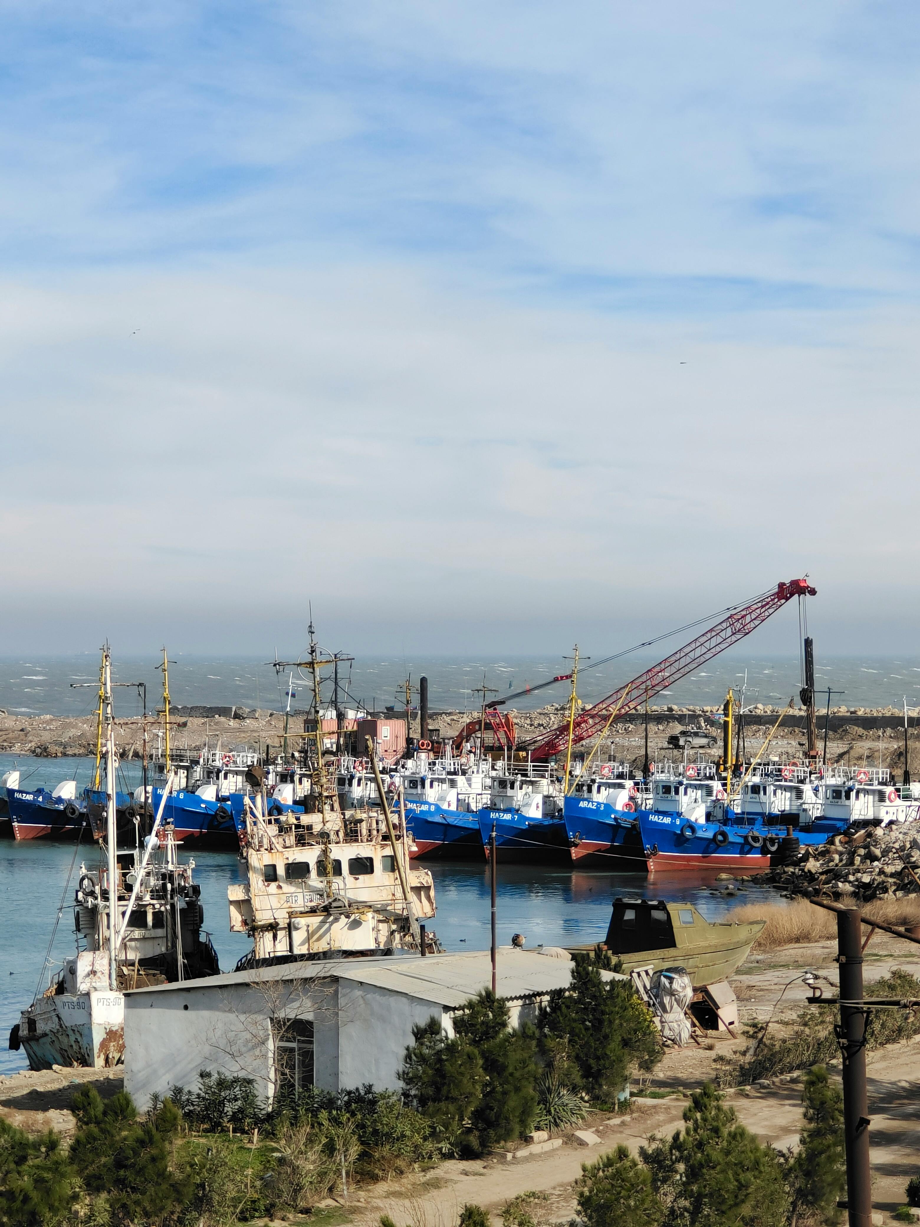 Gratis Vista panoramica di un porto peschereccio in Azerbaigian con barche e gru sotto un cielo limpido. Foto a disposizione
