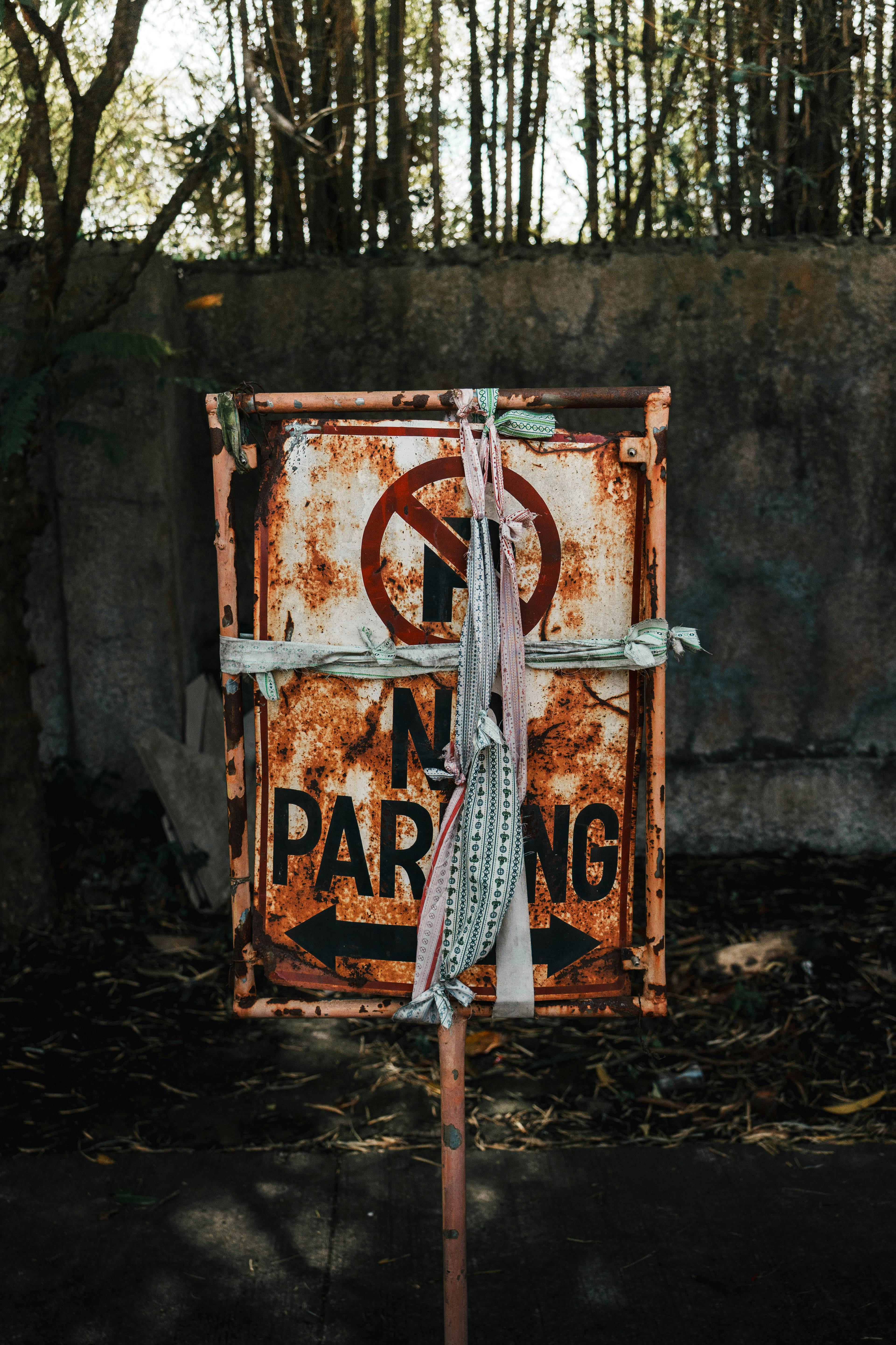 Ilmainen Ruosteinen ja sään kuluma "Pysäköinti kielletty" -kyltti ulkotiloissa, sidottu kankaalla. Kuvapankkikuva