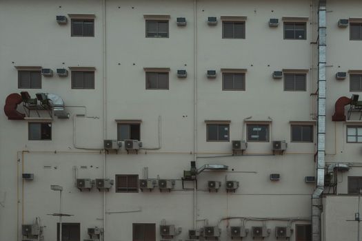 A building facade covered with air conditioning units and ducts illustrating urban architecture.