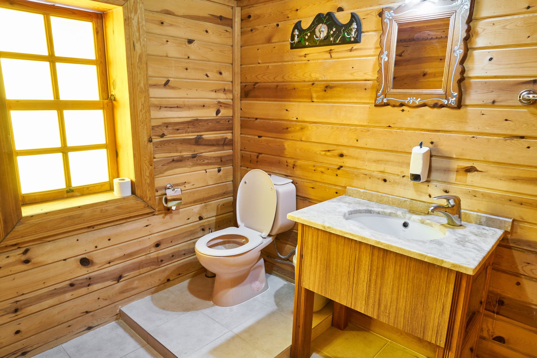 Compact rustic bathroom with substantial warm wood surfaces and soft light