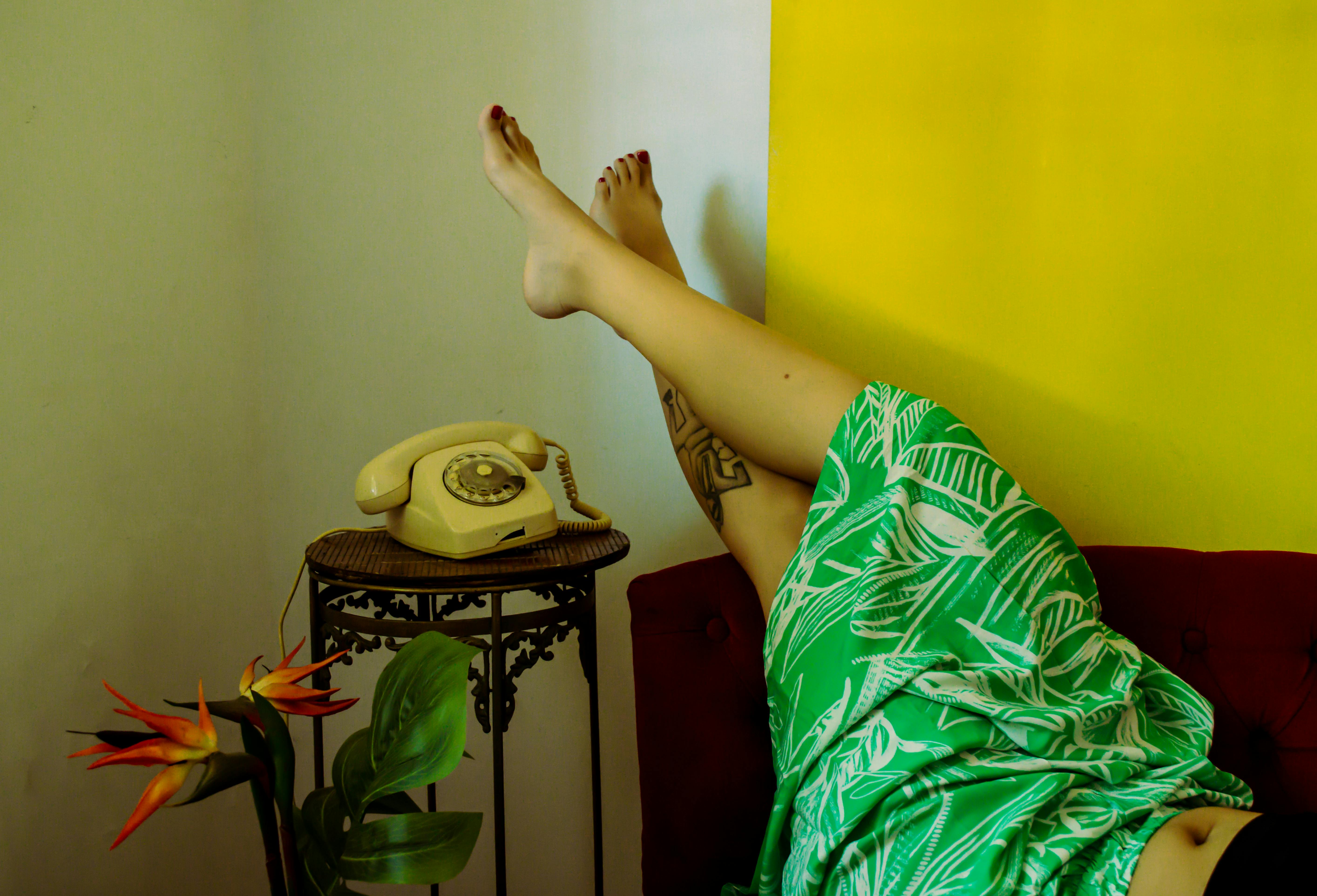 Gratis Mujer con vestido verde con teléfono vintage y planta tropical en el interior. Foto de stock