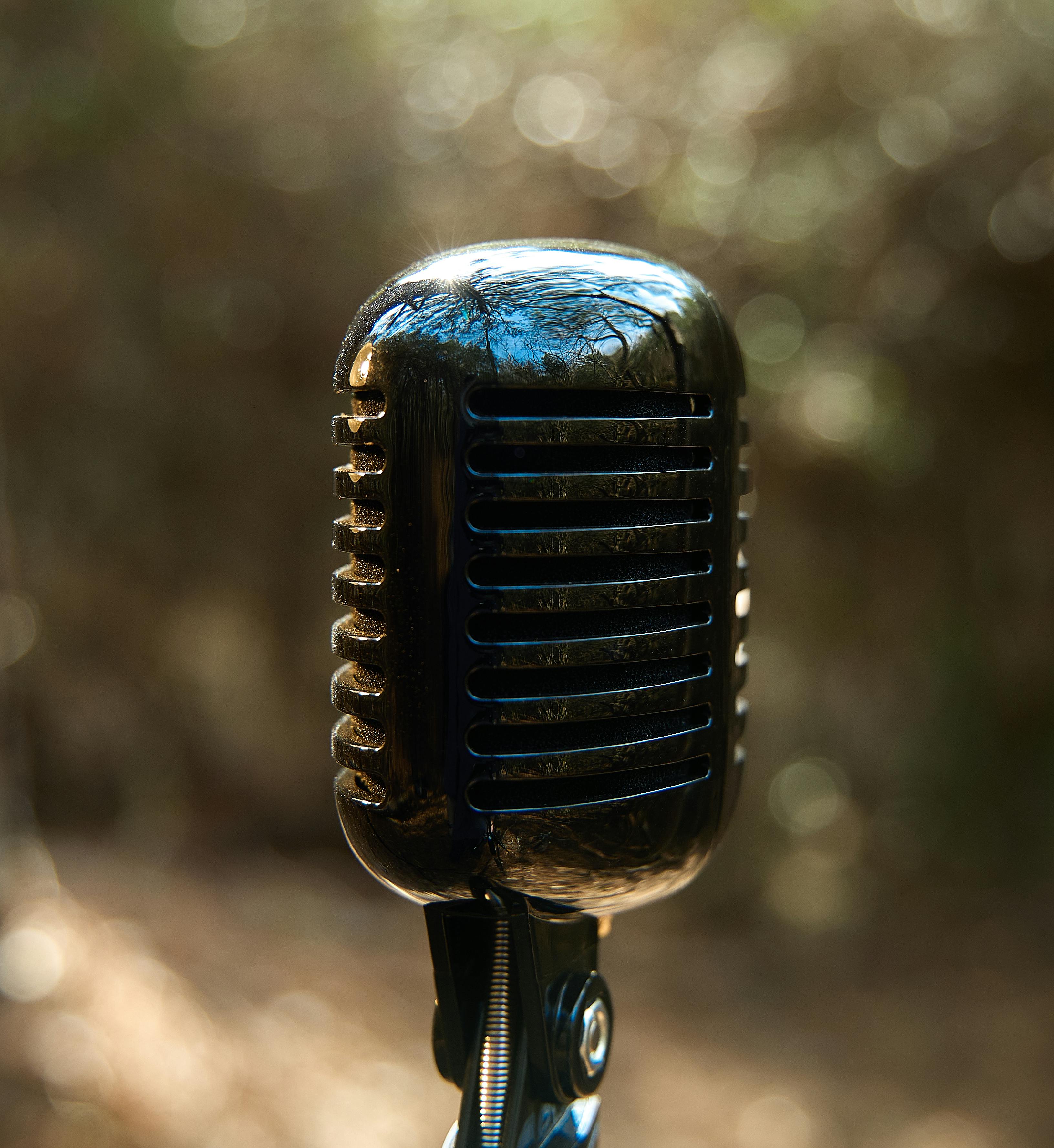 Free Close-up of a classic vintage microphone set against a soft blurred outdoor background. Stock Photo
