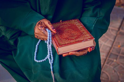 Close-up of a woman's hands holding a religious book with prayer beads.