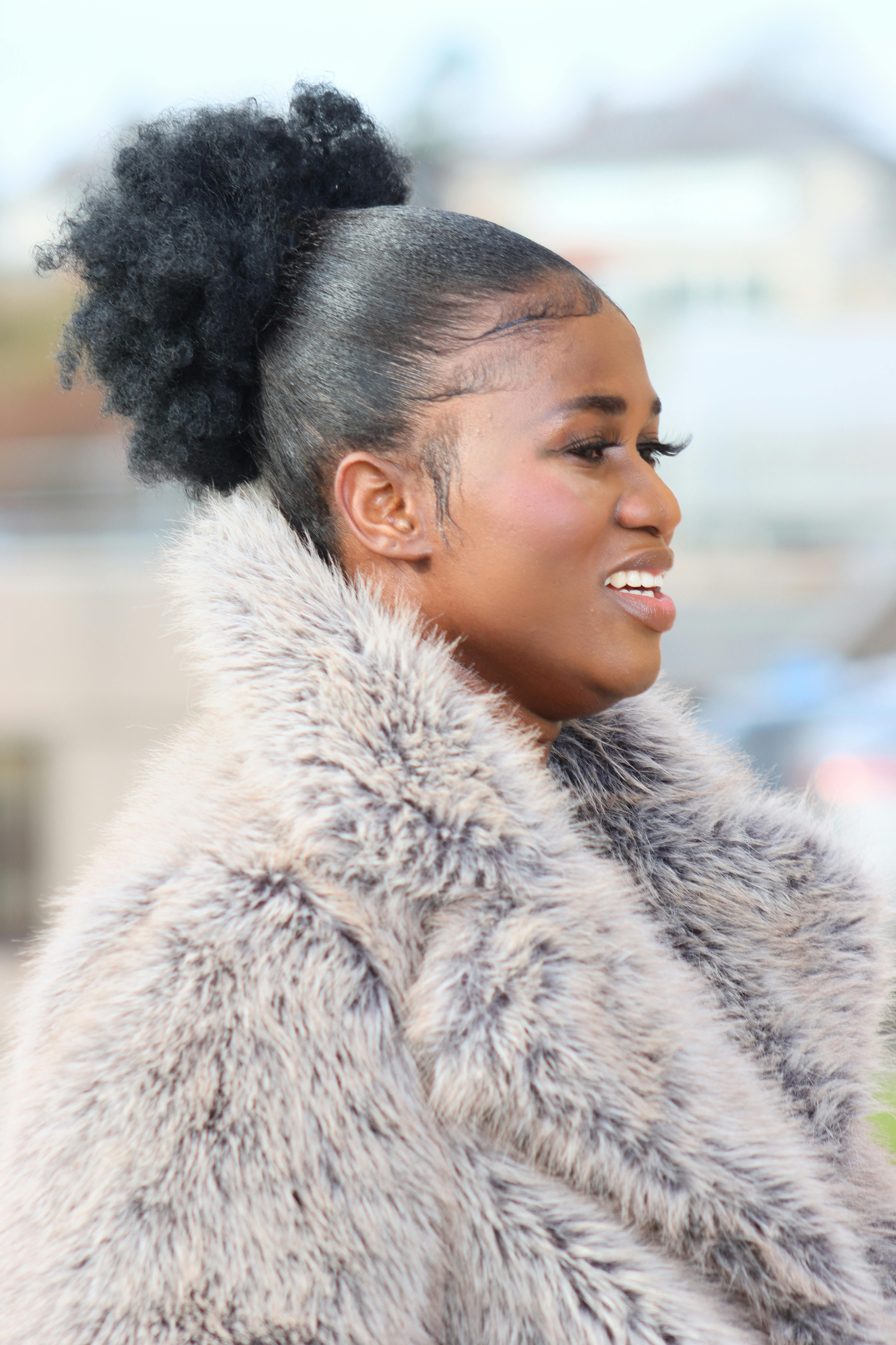 Ilmainen Hymyilevän turkkiin pukeutuneen naisen profiili ulkona, joka osoittaa eleganssia ja itsevarmuutta. Kuvapankkikuva