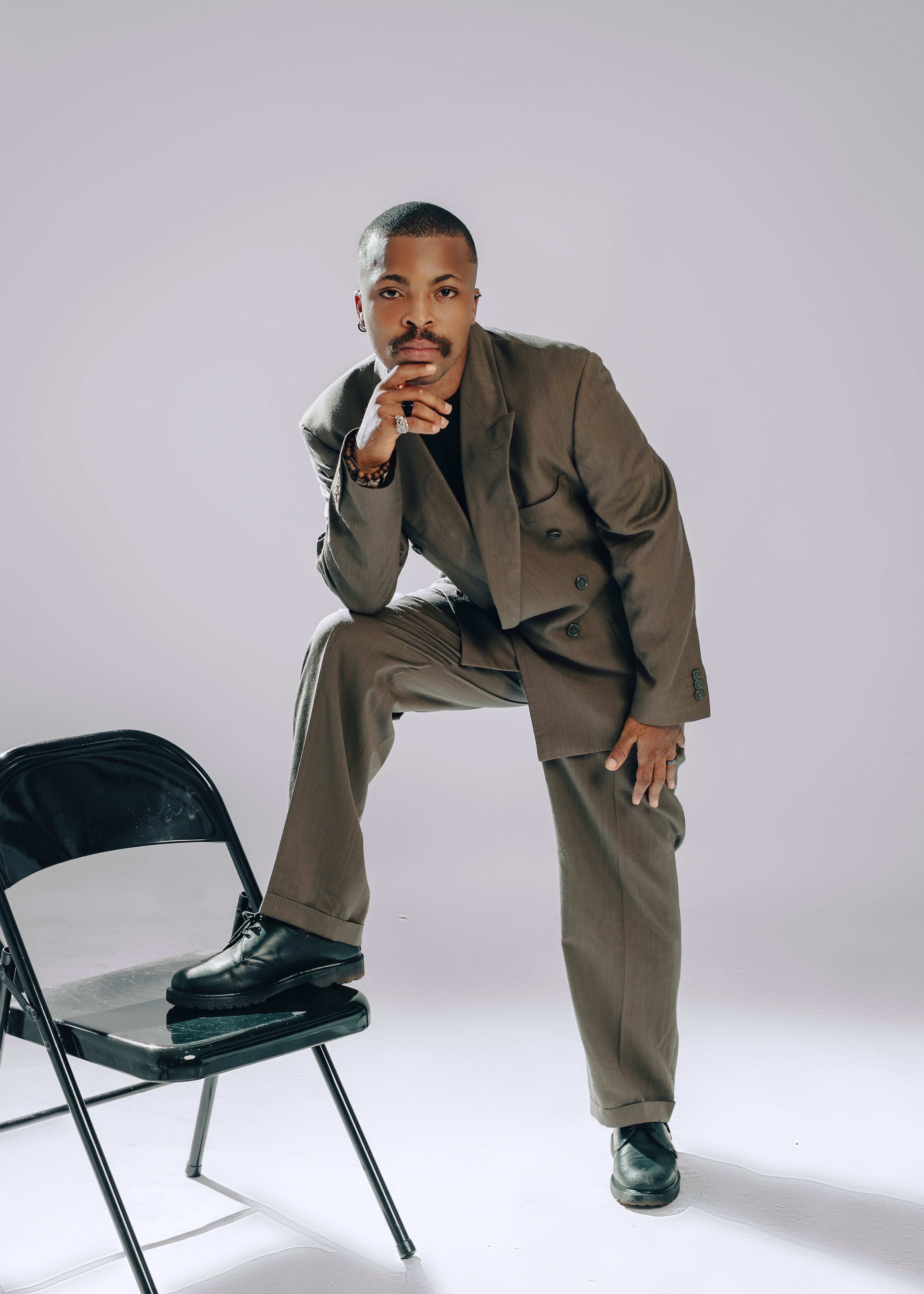 Confident male model in a classic suit strikes a stylish pose indoors.