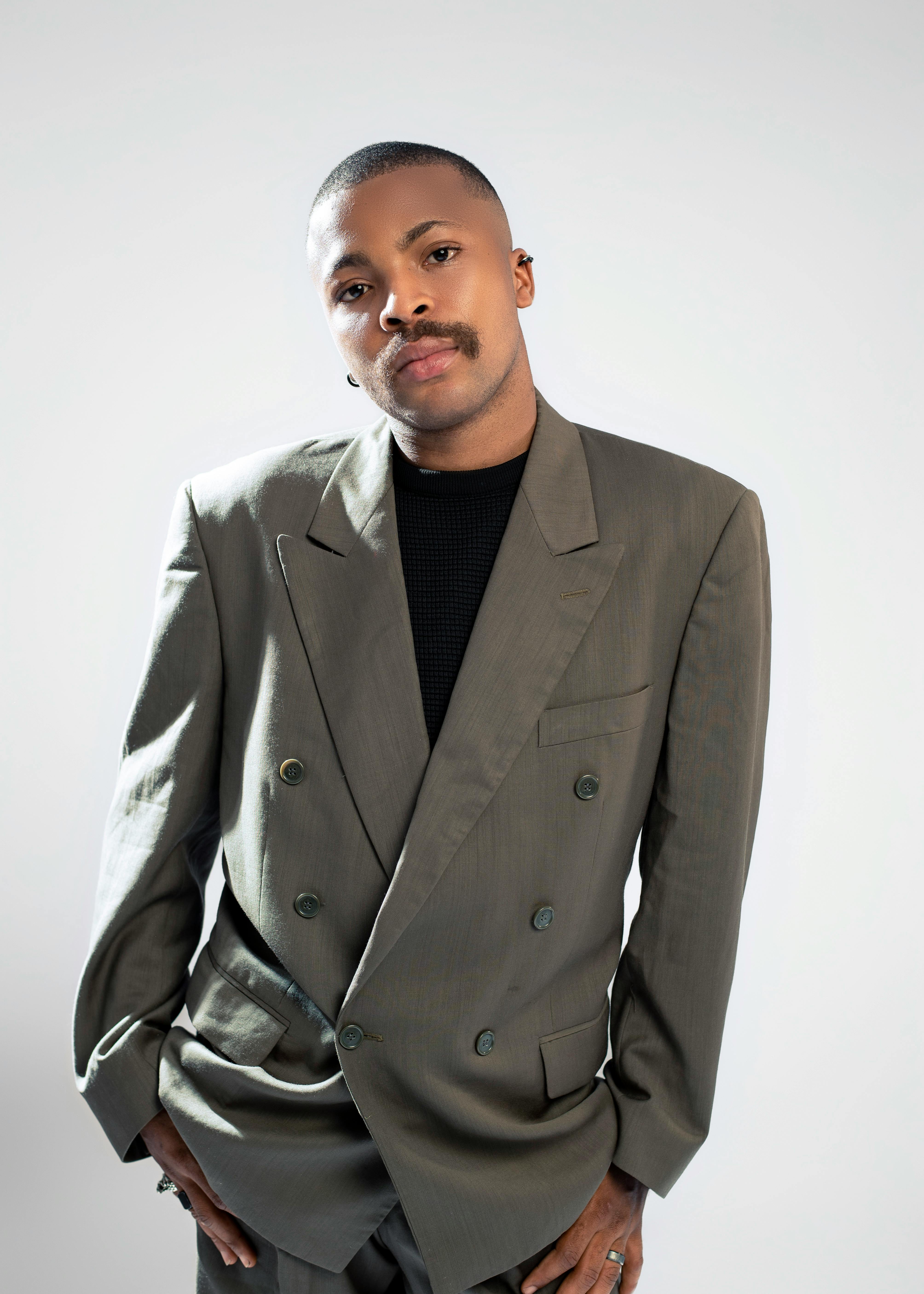 Ilmainen Itsevarma mies poseeraa tyylikkäässä puvussa neutraalilla taustalla. Kuvapankkikuva