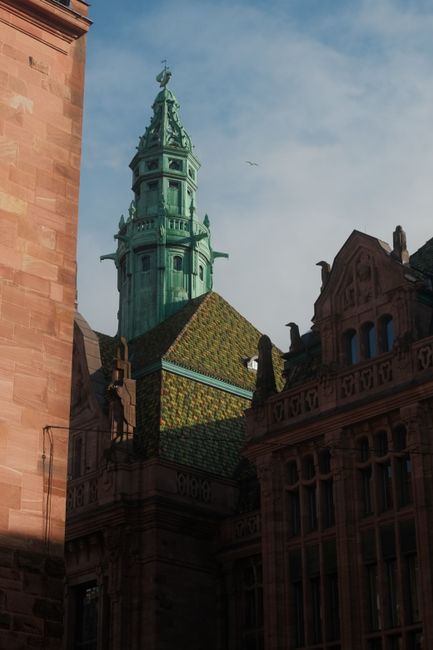 Captivating view of a historic building with a green-tiled tower against a clear sky.