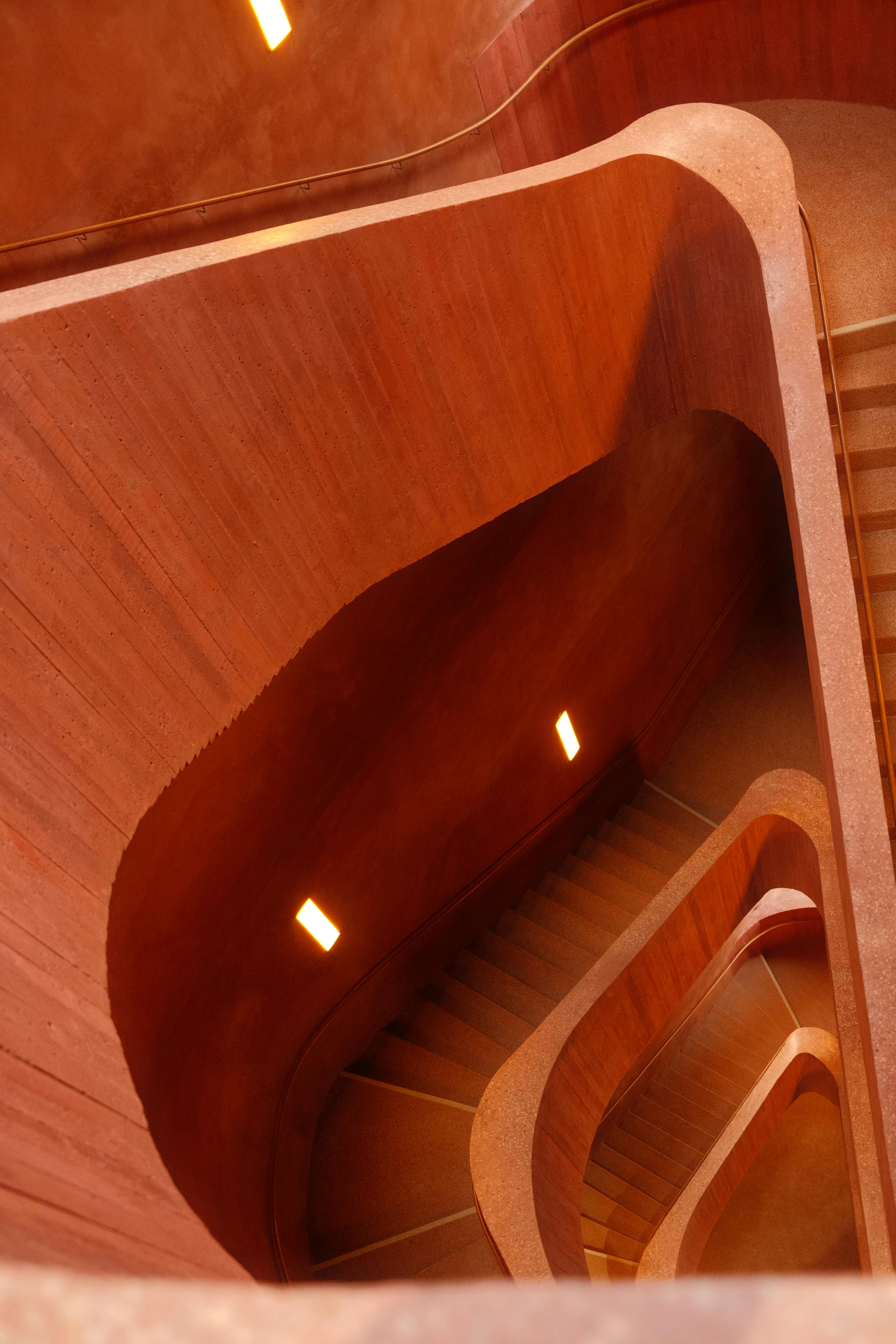 Ücretsiz Sıcak aydınlatmaya sahip kavisli mimari merdiven, modern ve benzersiz bir görsel etki yaratıyor. Stok Fotoğraflar