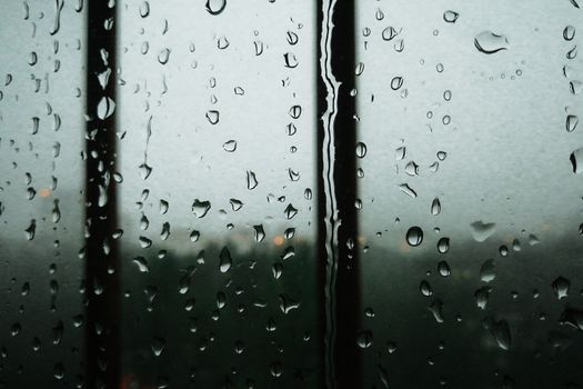Raindrops on a window glass creating a serene and moody atmosphere.