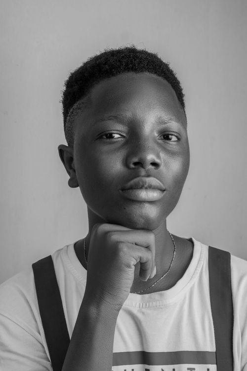 Free A thoughtful black and white portrait of a young man resting his chin on his hand. Stock Photo
