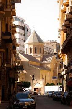 A scenic view of a historic church nestled between urban buildings on a sunny day.