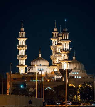 Illuminated mosque architecture captured at night in Kuwait City, showcasing Islamic design and elegance.