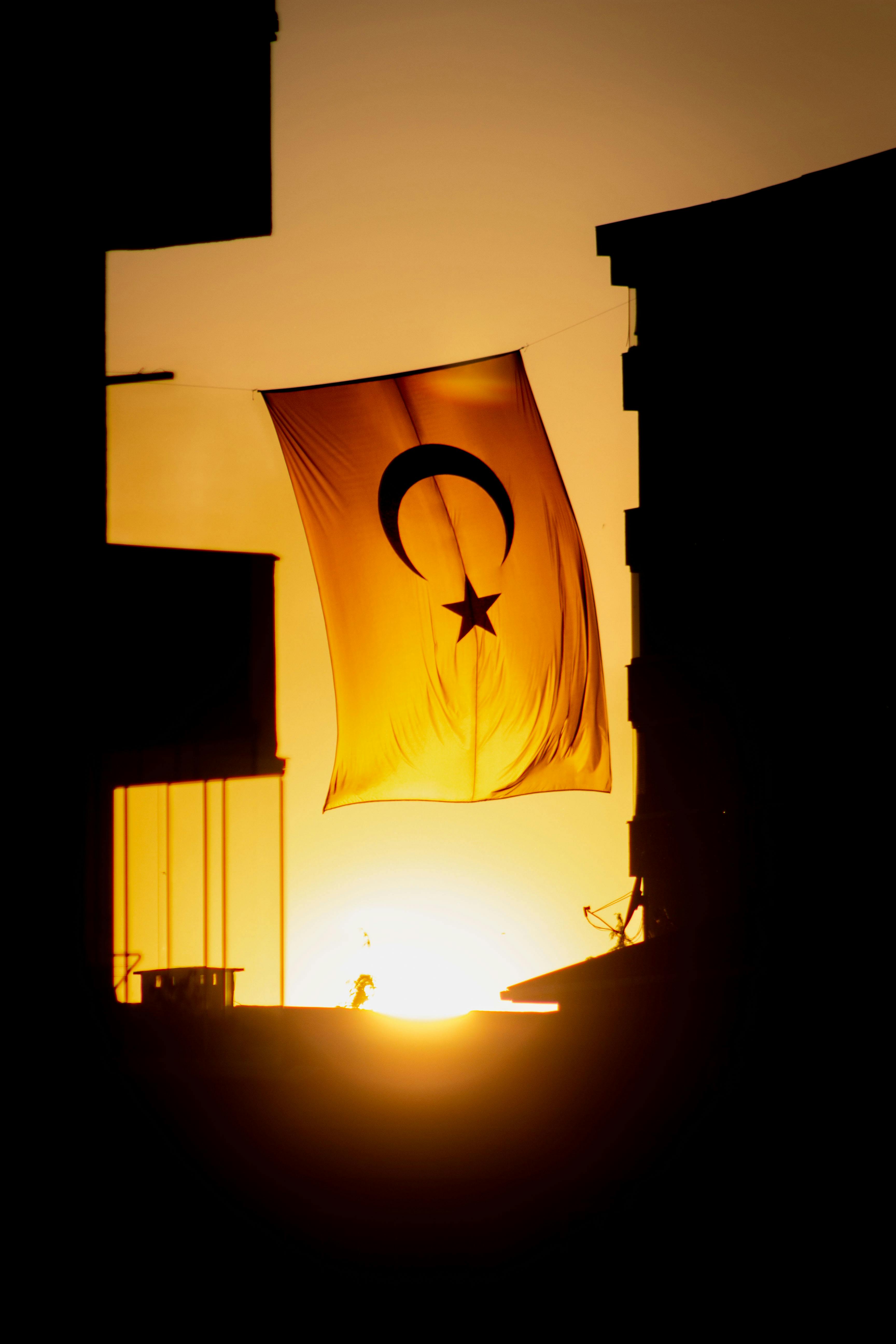 Gratis La bandiera turca si staglia al tramonto, sventolando tra gli edifici di Istanbul. Foto a disposizione