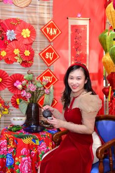 Woman celebrating Lunar New Year with colorful traditional decorations indoors.