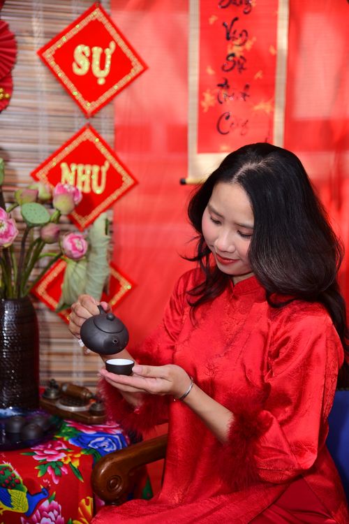 Free A woman in traditional attire pours tea, celebrating Vietnamese Lunar New Year. Stock Photo