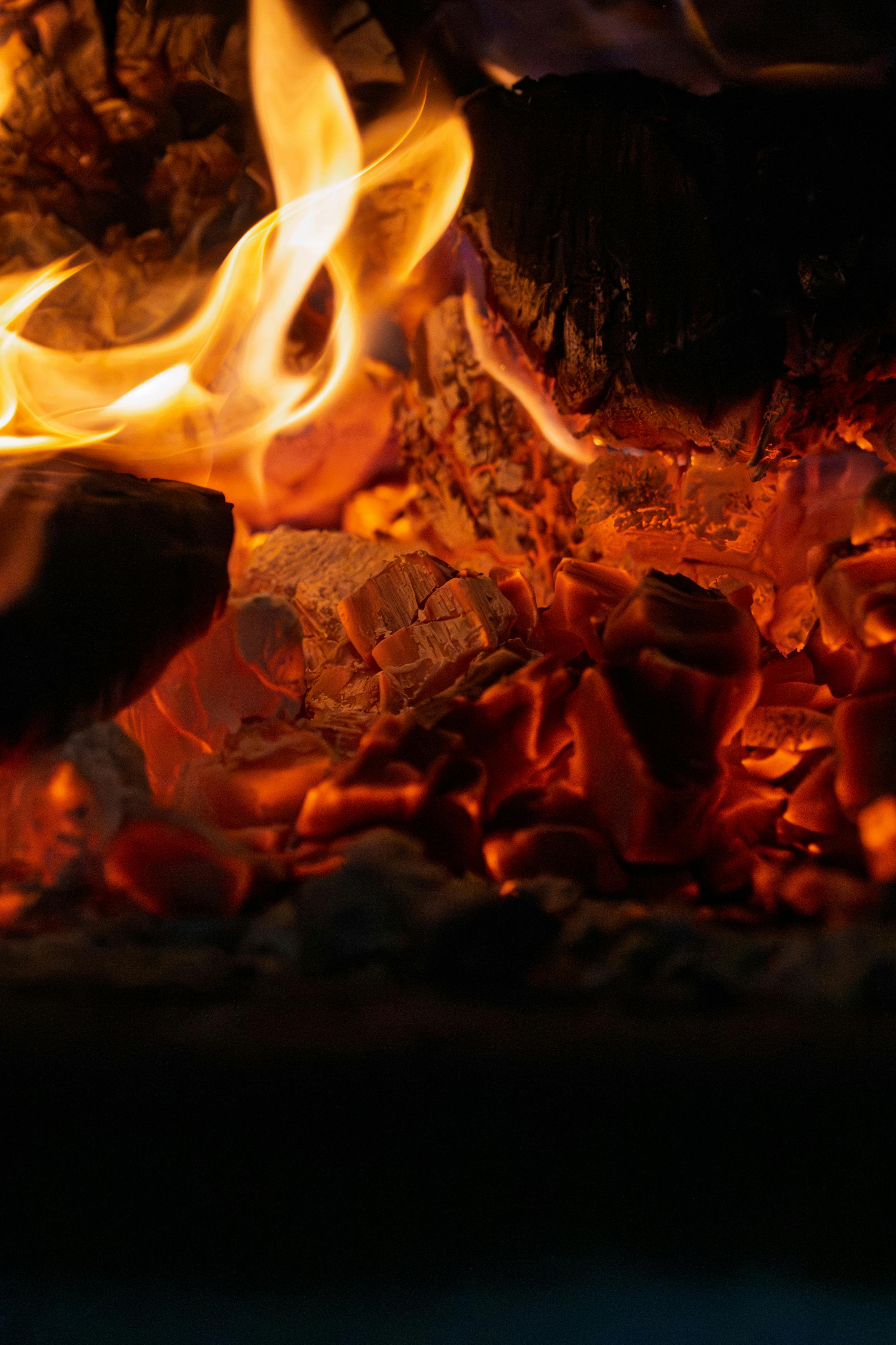 Ilmainen Yksityiskohtainen kuva palavista hiilistä ja niiden eloisista liekeistä, jotka vangitsevat voimakkaan kuumuuden ja monimutkaiset tekstuurit. Kuvapankkikuva