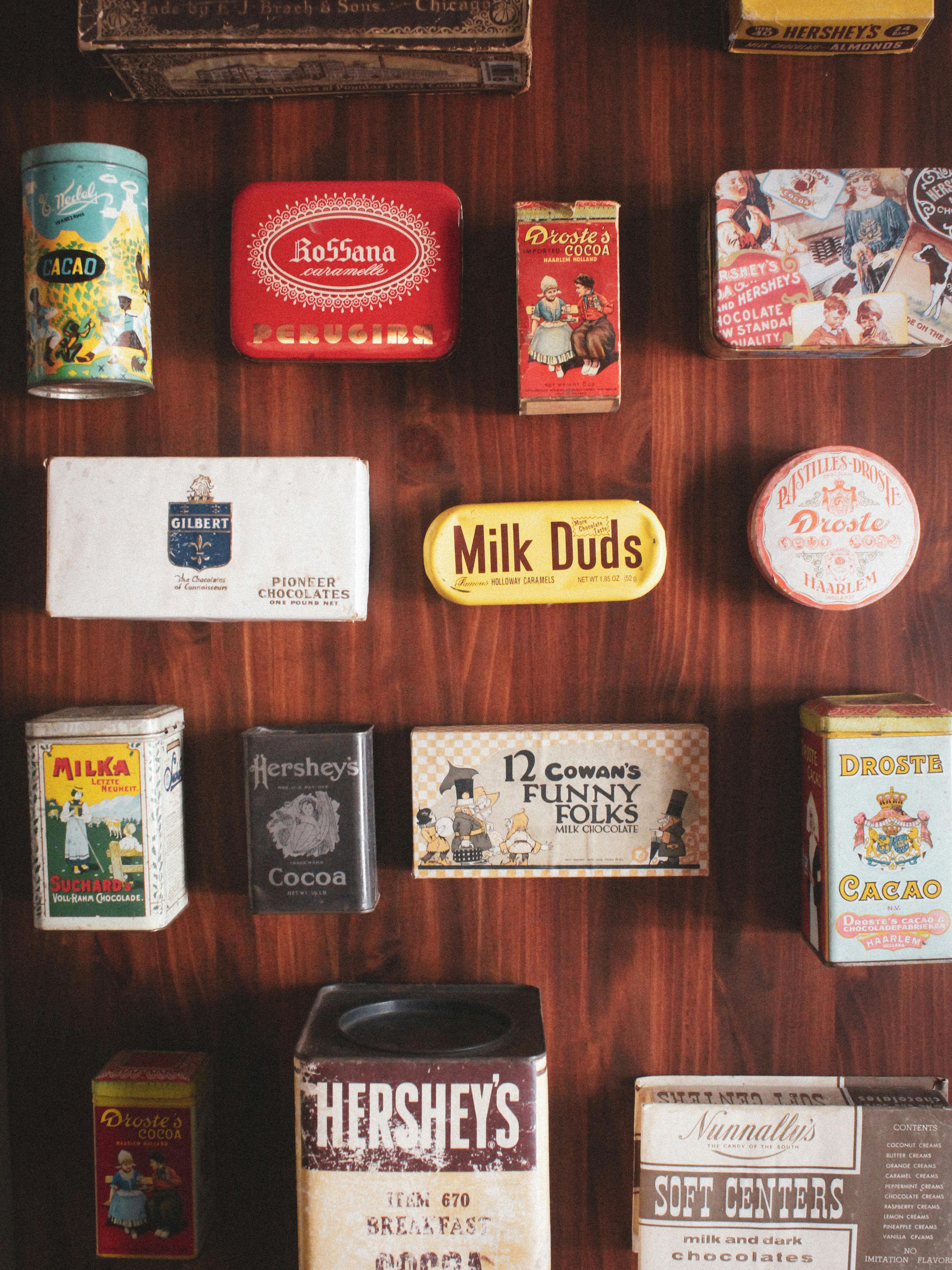 Ilmainen Kokoelma vintage-suklaapurkkeja puupinnalla, esittelemässä retrohenkistä pakkausmuotoilua. Kuvapankkikuva