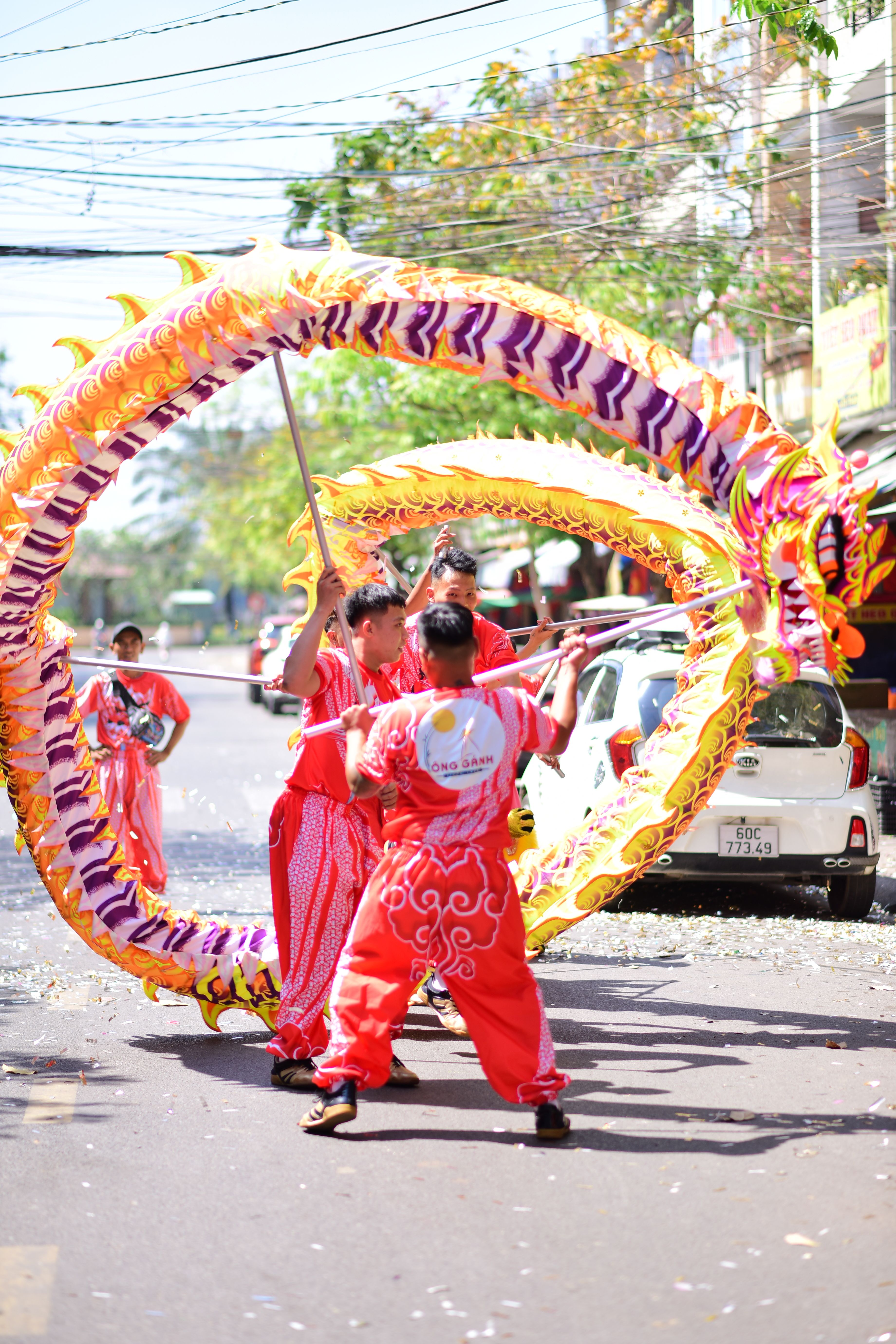 Colorful dragon dance performance on a sunny street during a festival.