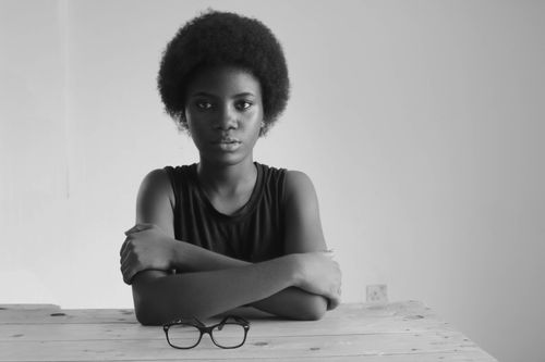 Free Striking monochrome portrait of a woman with afro hair seated at a table. Stock Photo