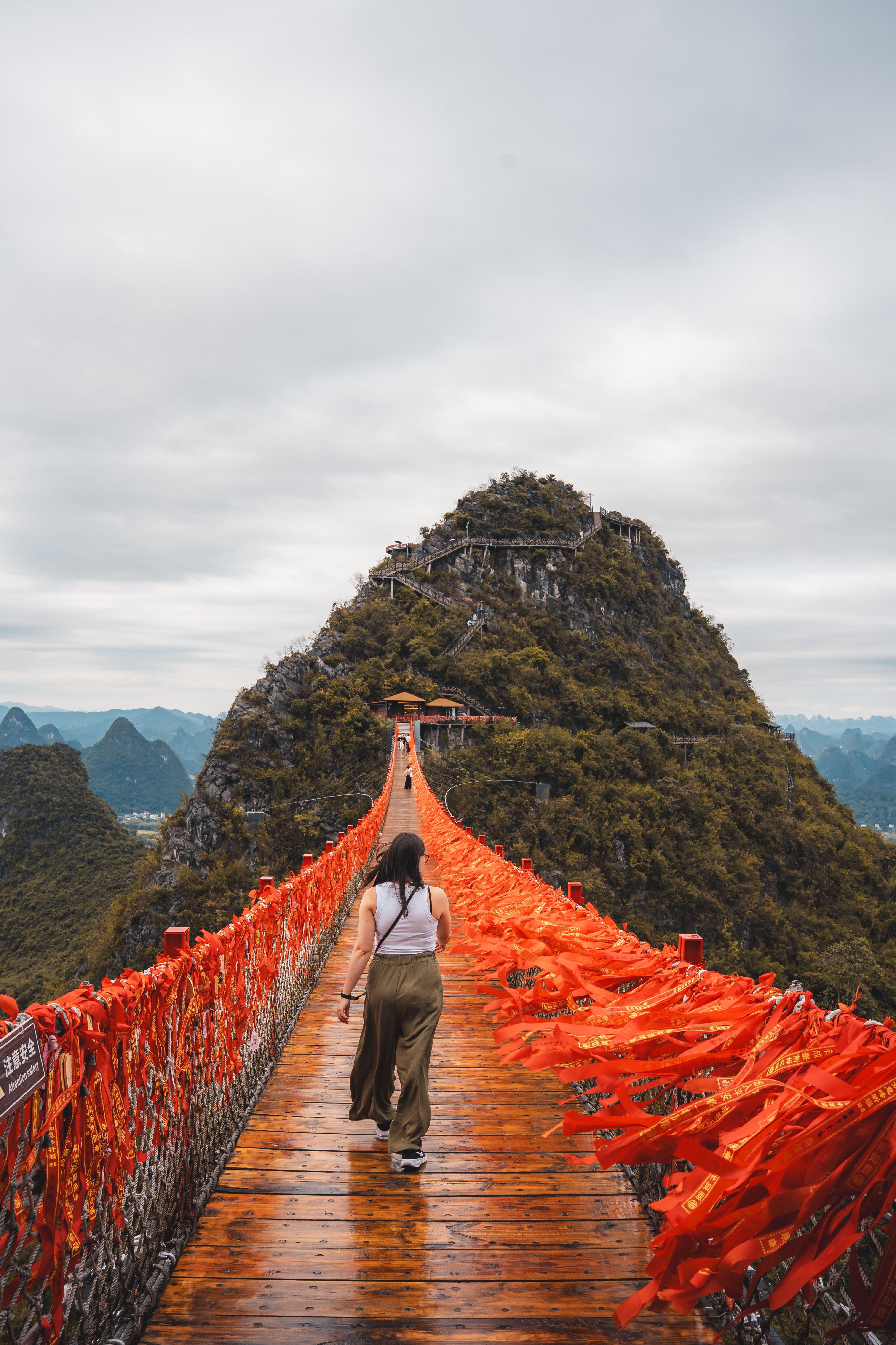 Woman Walking on Red Ribbon Bridge in Guilin Mountains · Free Stock Photo