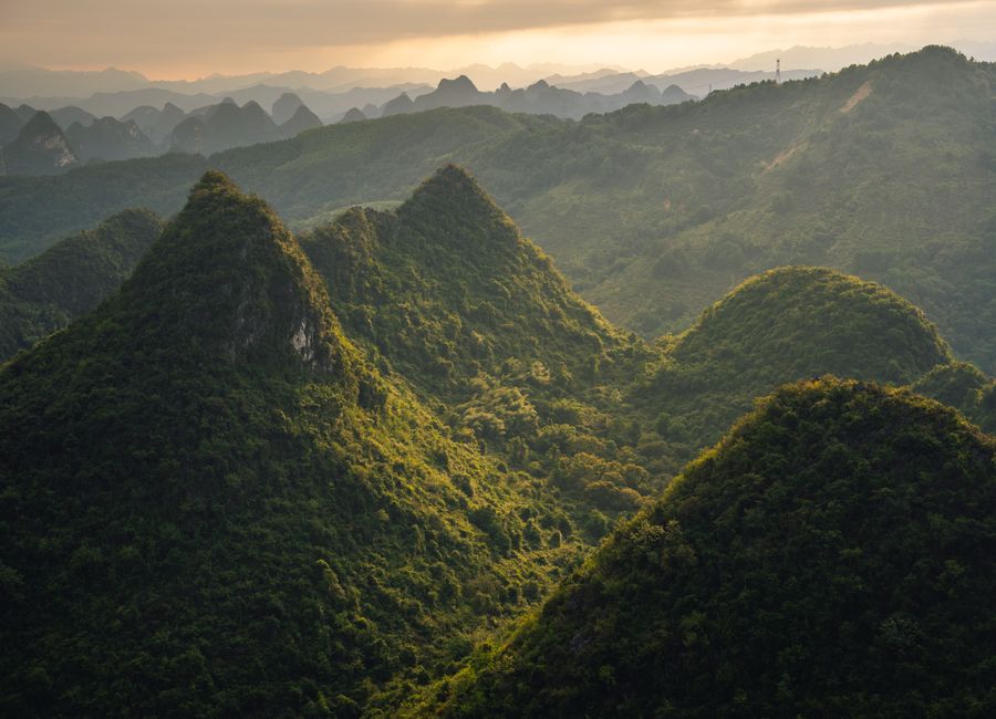 Stunning aerial view of lush green karst mountain landscape in Guilin, Guangxi, China during sunset.