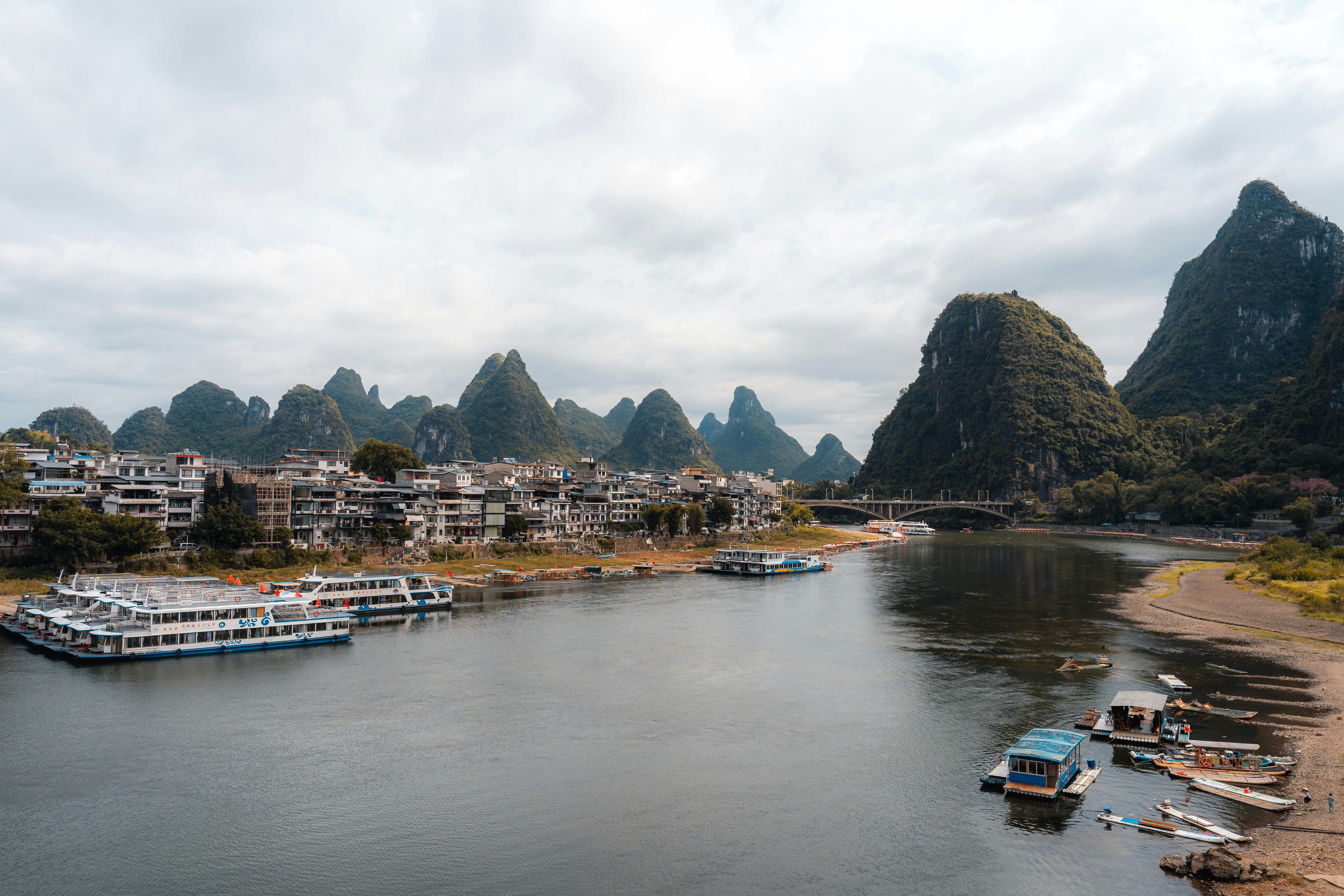 Li River cruise boat sailing through karst mountain peaks and misty green waters between Guilin and Yangshuo in Guangxi China at sunrise