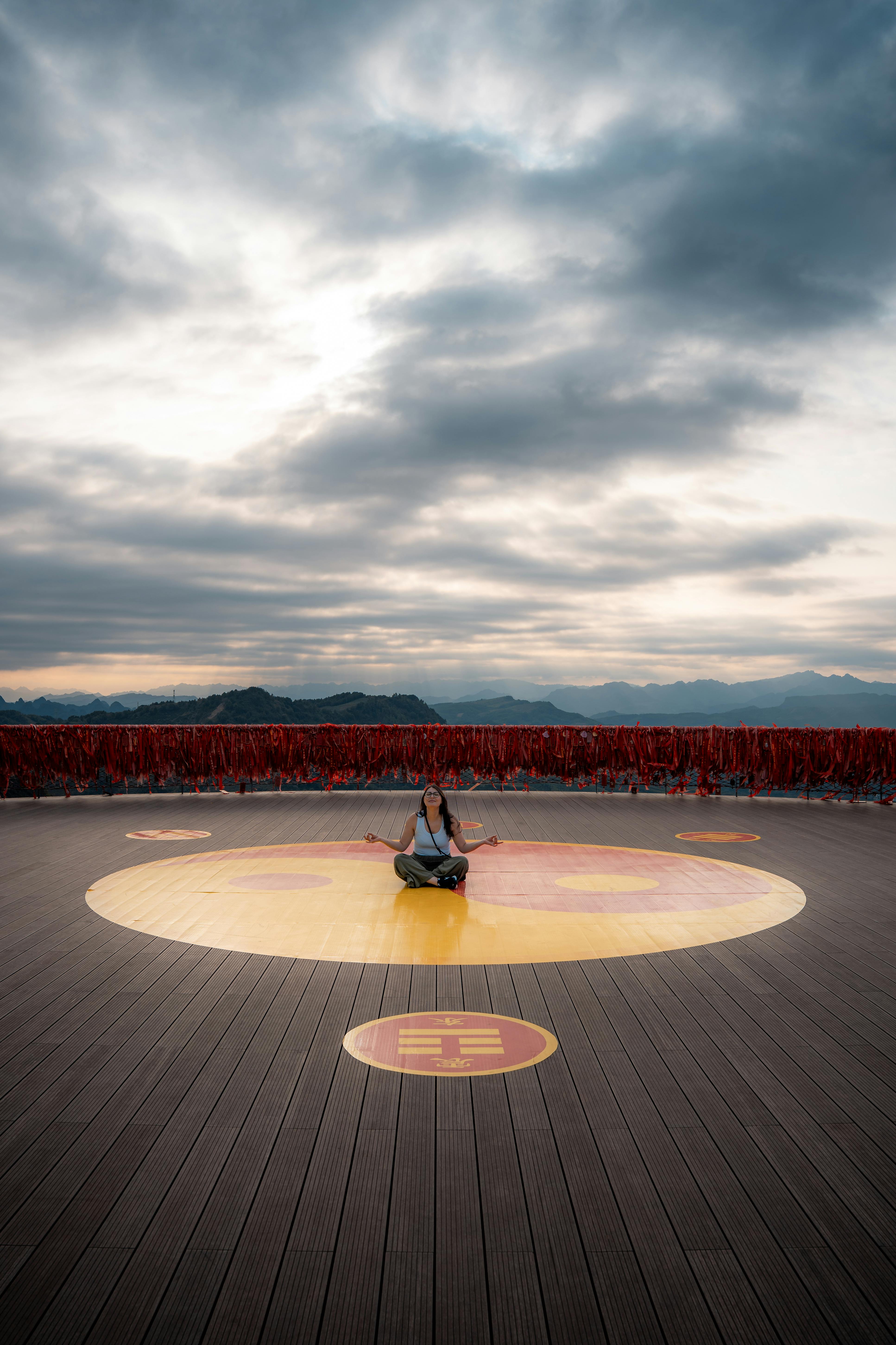 Free Person meditating on a platform in Guilin, China, with mountains under a dramatic sky. Stock Photo