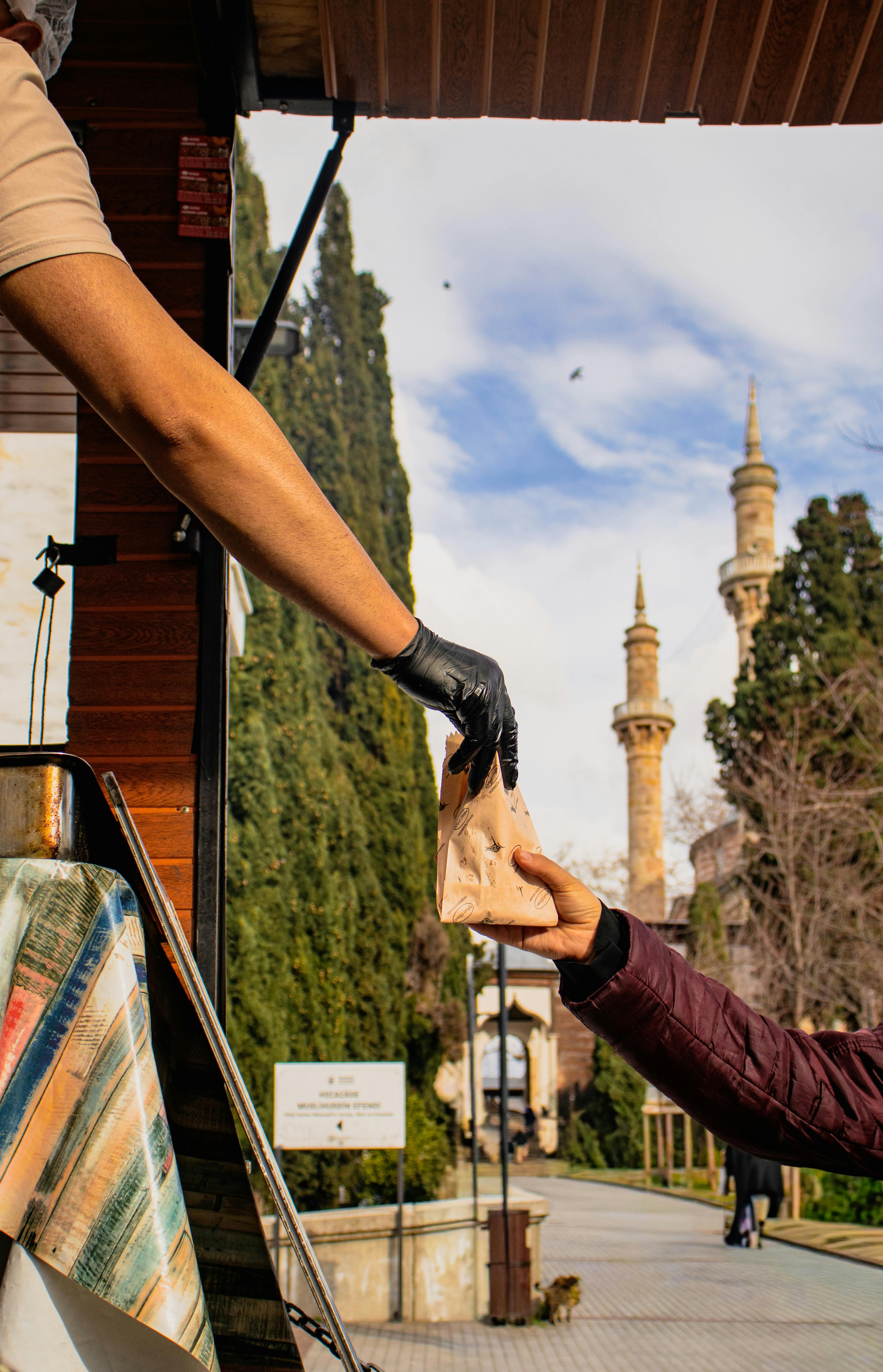 Ilmainen Katukauppias ojentaa kassin asiakkaalle historiallisten rakennusten lähellä. Kuvapankkikuva