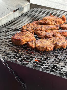 Juicy, marinated meat sizzling on an outdoor grill in Kuantan, Malaysia.