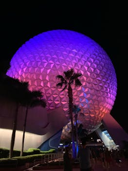 Colorful night view of Epcot's geodesic sphere with illuminated architectural design. by Kendall Carey