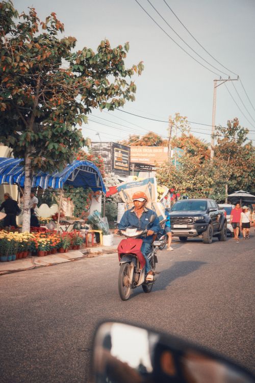 Free A vibrant street scene featuring a motorbike rider in a lively market area, suggesting everyday life in a bustling town. Stock Photo