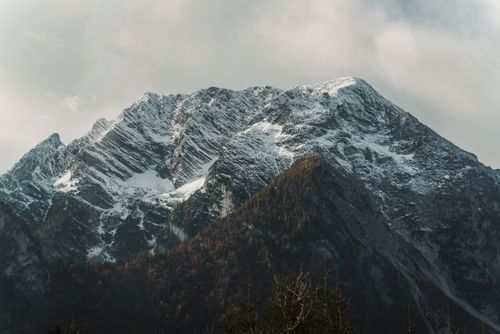 Free Capture the dramatic beauty of a snow-covered mountain peak amidst a rugged landscape. Ideal for adventure and travel themes. Stock Photo