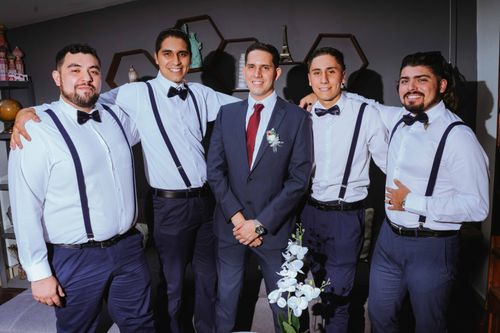 Free Group of five men in formal attire, showcasing a joyful wedding party moment indoors. Stock Photo