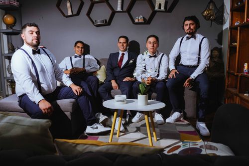 Free Group of groomsmen in stylish formal attire, sitting indoors with modern decor. Stock Photo