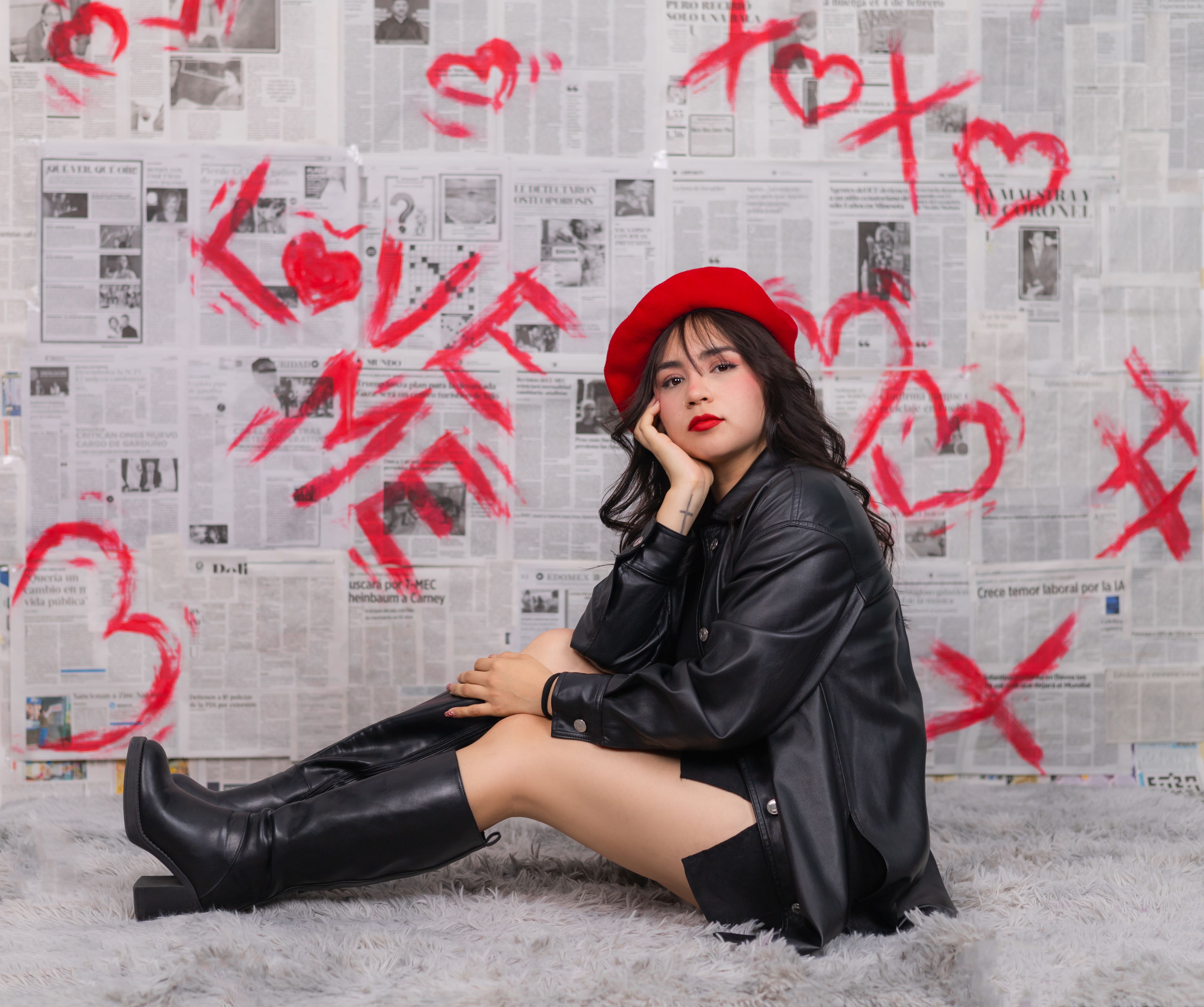 Woman wearing a red beret and black outfit against a love-themed newspaper wall.