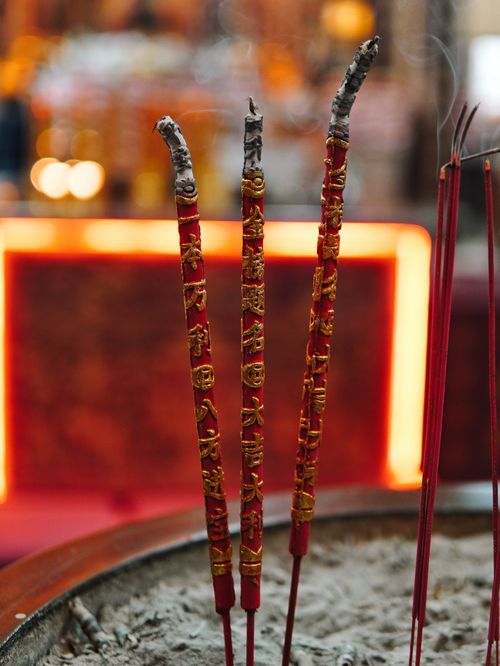 Free Close-up of incense sticks burning in a temple setting with glowing background. Stock Photo