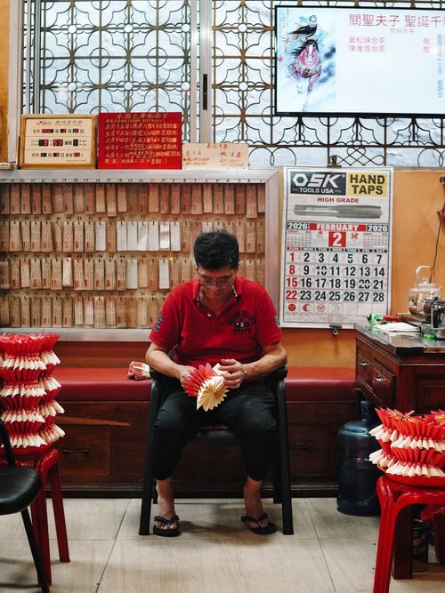 Free Senior man folding paper decorations in a traditional shop setting. Stock Photo