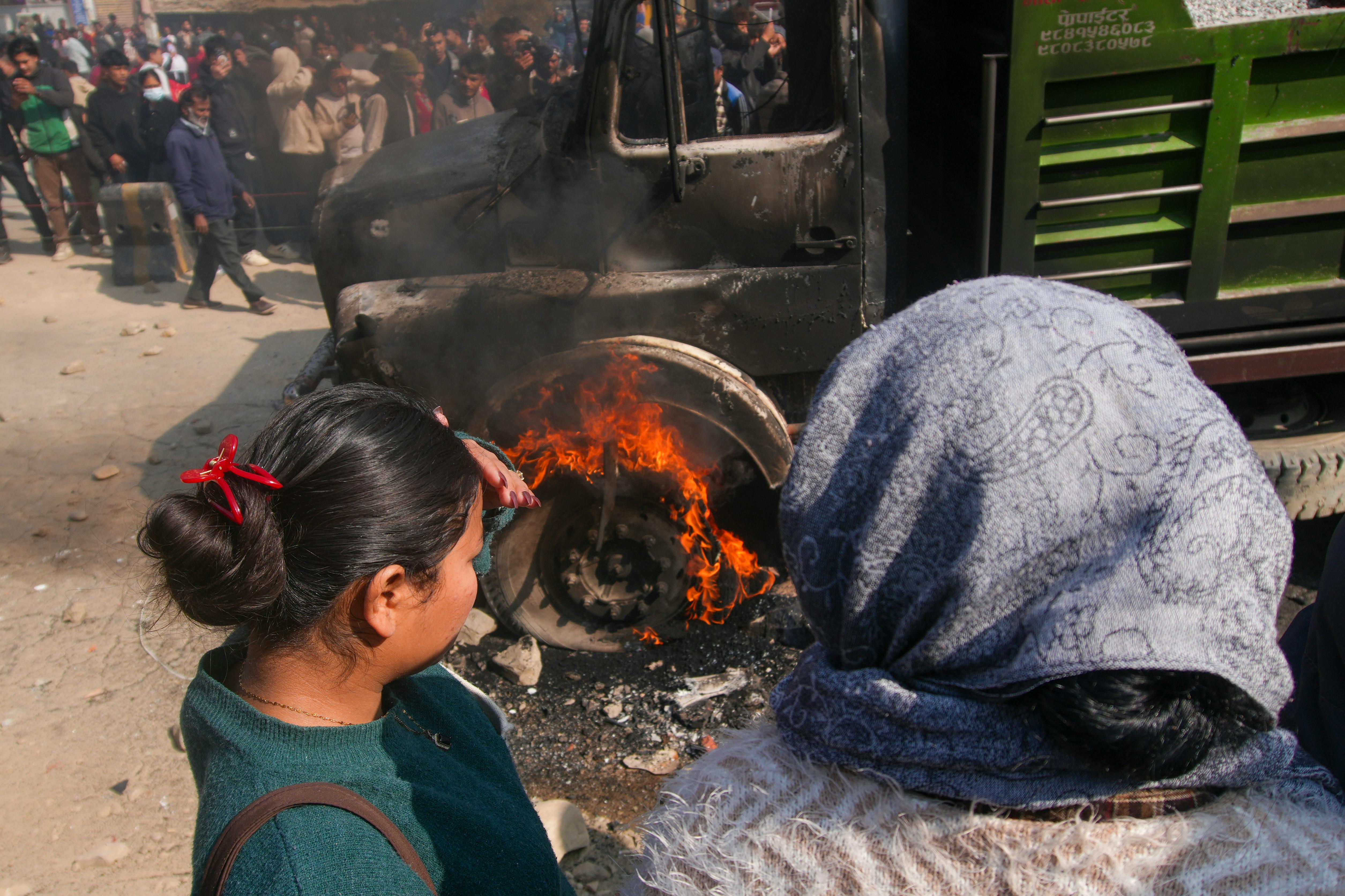 A group of people watch a truck fire in a crowded city street, capturing an intense moment.