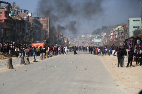 Free Large crowd gathered during a peaceful street demonstration with smoke in the background in a cityscape setting. Stock Photo