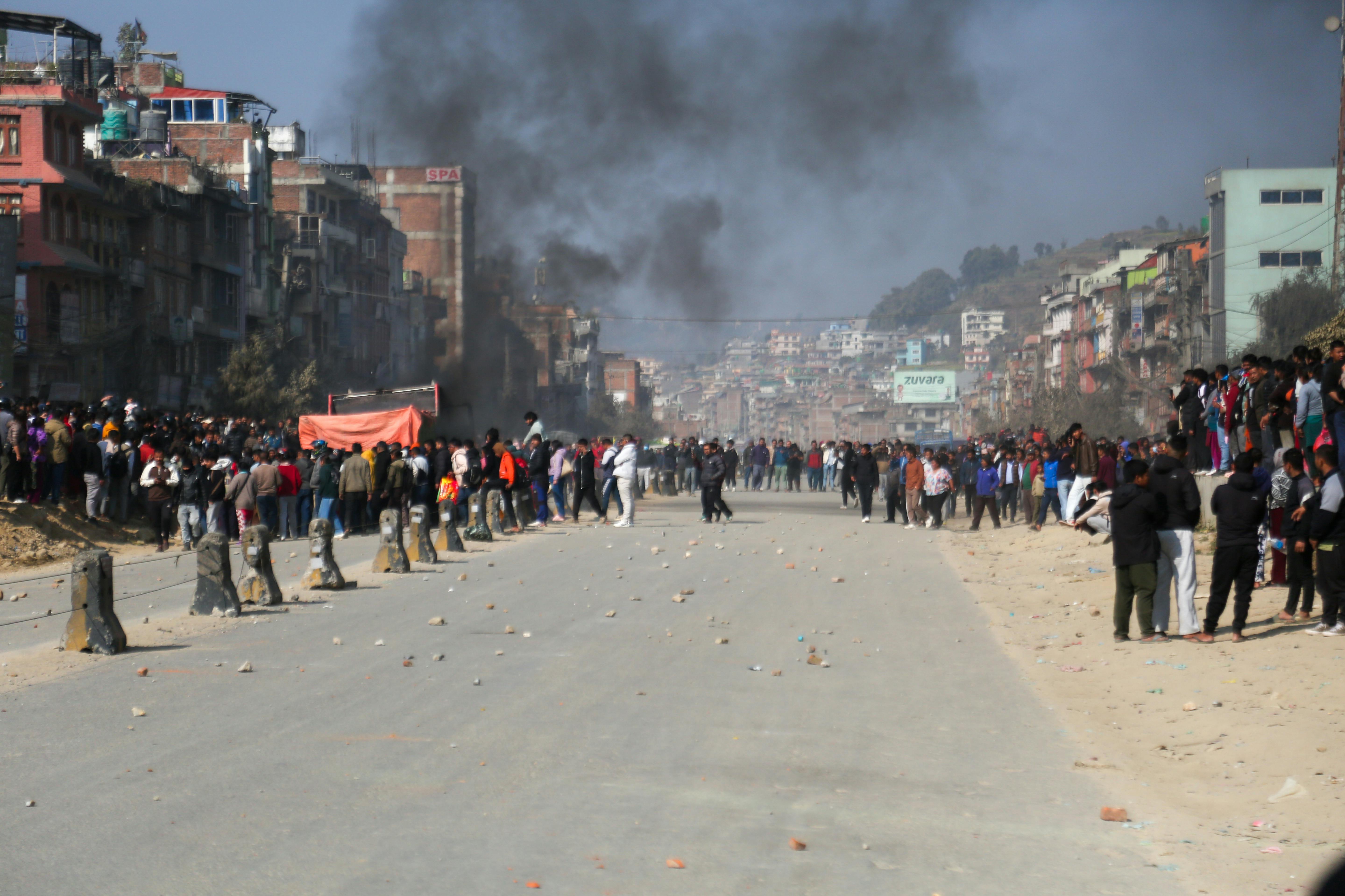 bezplatná Velký dav se shromáždil během pokojné pouliční demonstrace s kouřem v pozadí v městském prostředí. Základová fotografie
