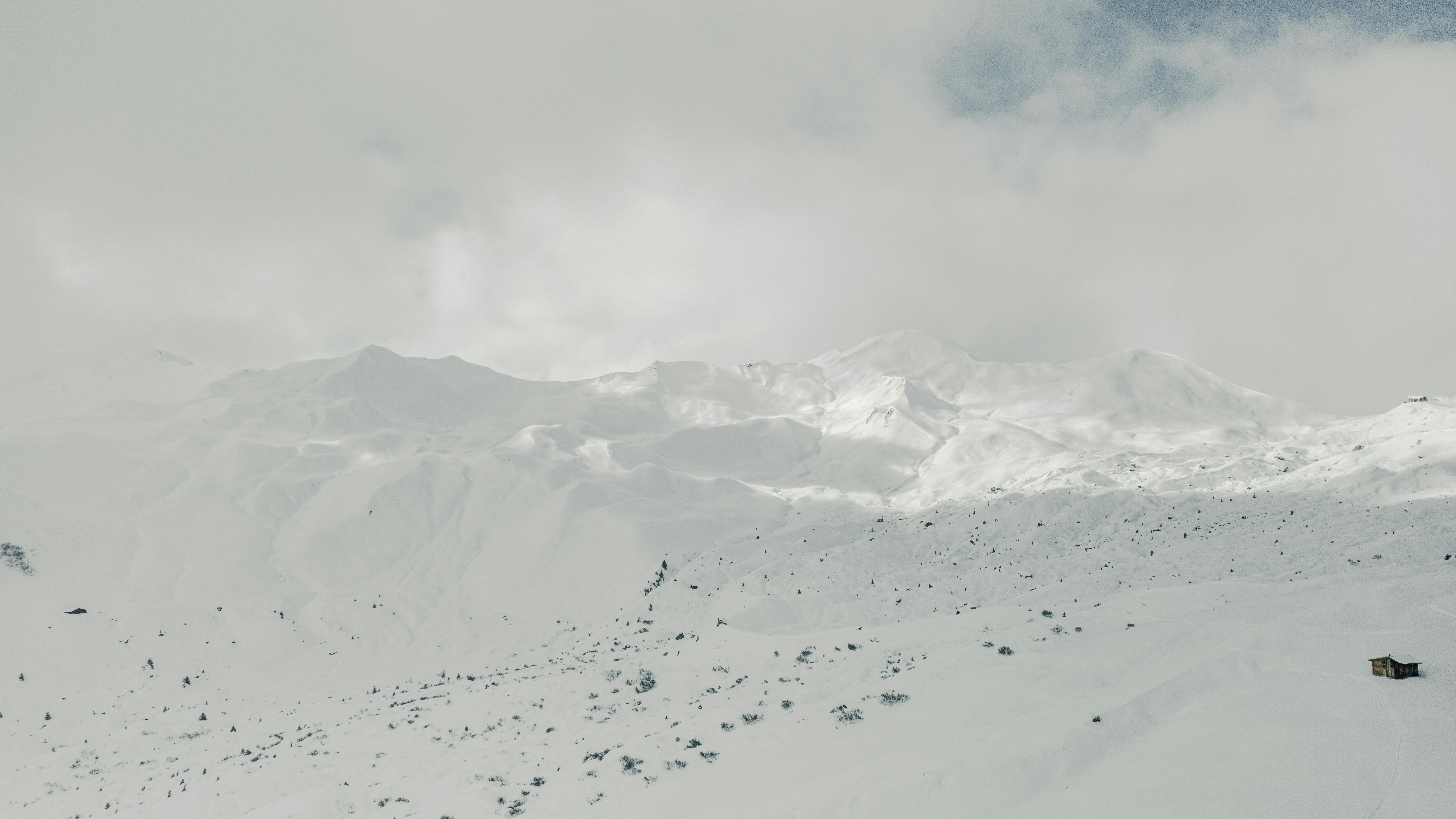 Ilmainen Henkeäsalpaava näkymä lumipeitteisille vuorille pilvisen talvitaivaan alla. Kuvapankkikuva