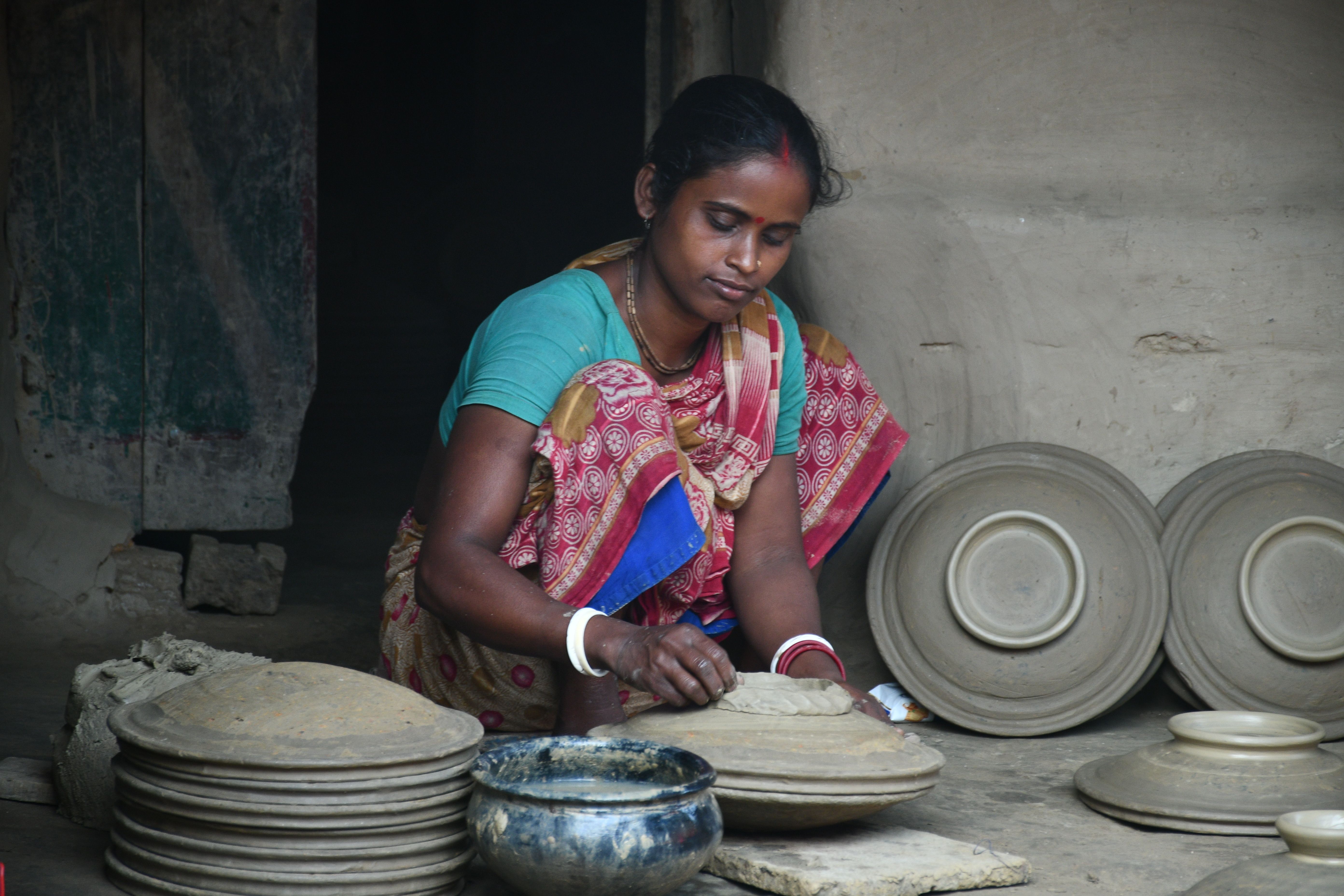 A traditional potter in Rangpur, Bangladesh skillfully crafting clay pottery.